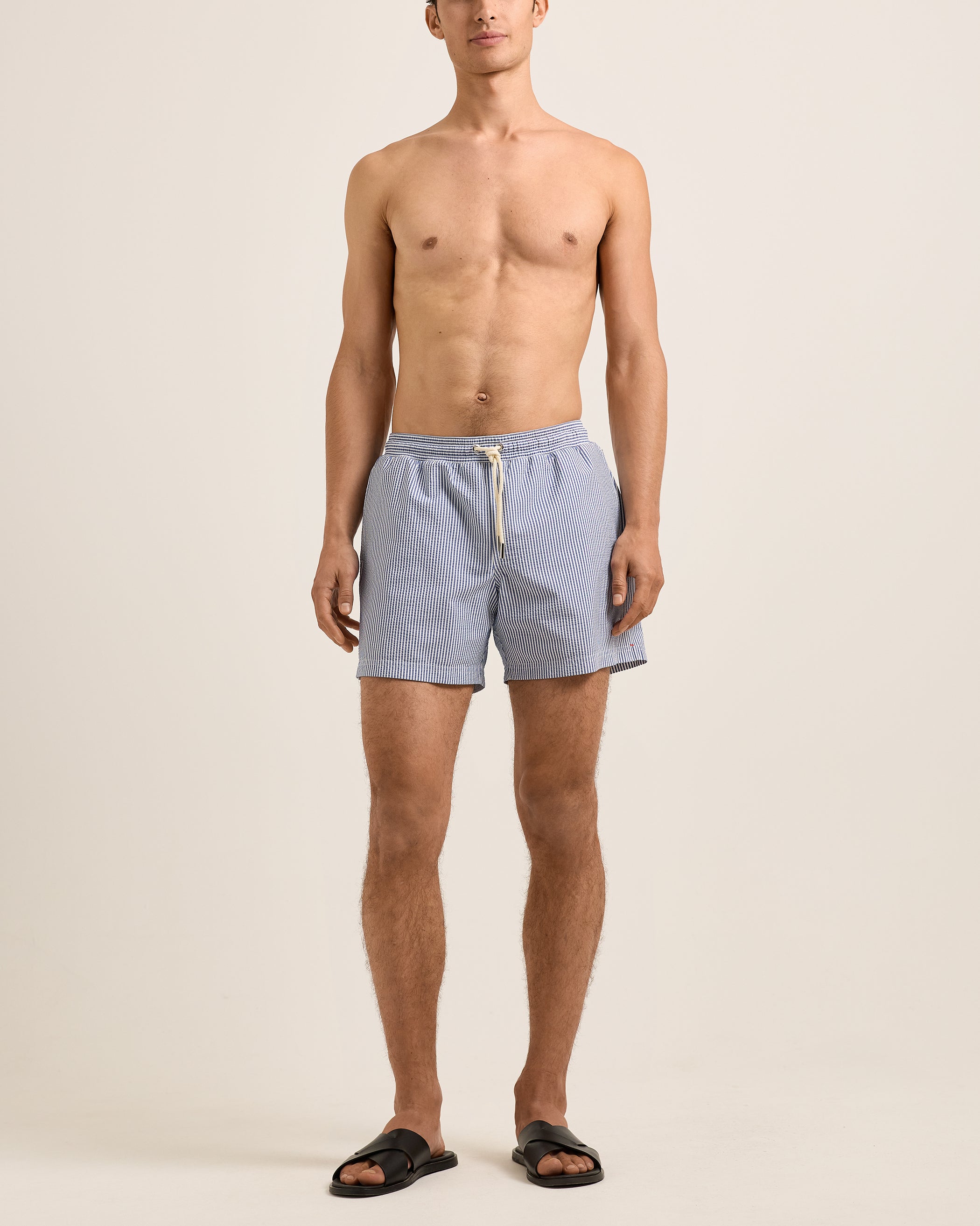 Man wearing light blue shorts on a beige background