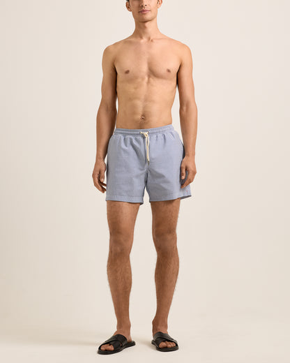 Man wearing light blue shorts on a beige background