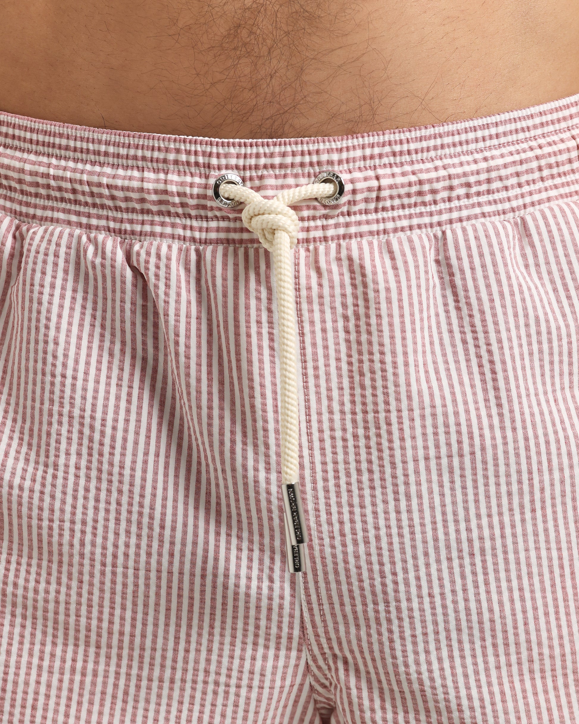 Close-up of red and white striped shorts with a drawstring on a person's waist.