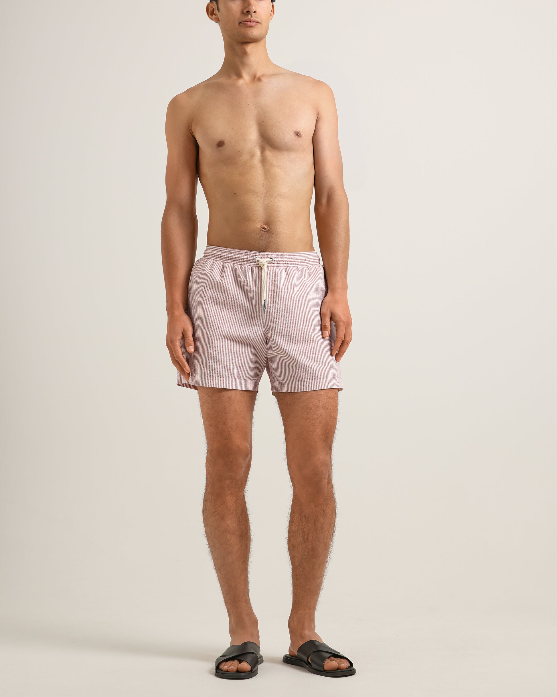 Man wearing light pink shorts on a plain background