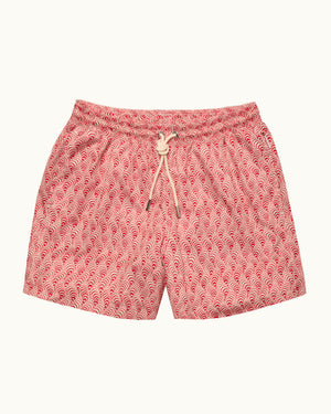 Red patterned swim shorts on a plain background