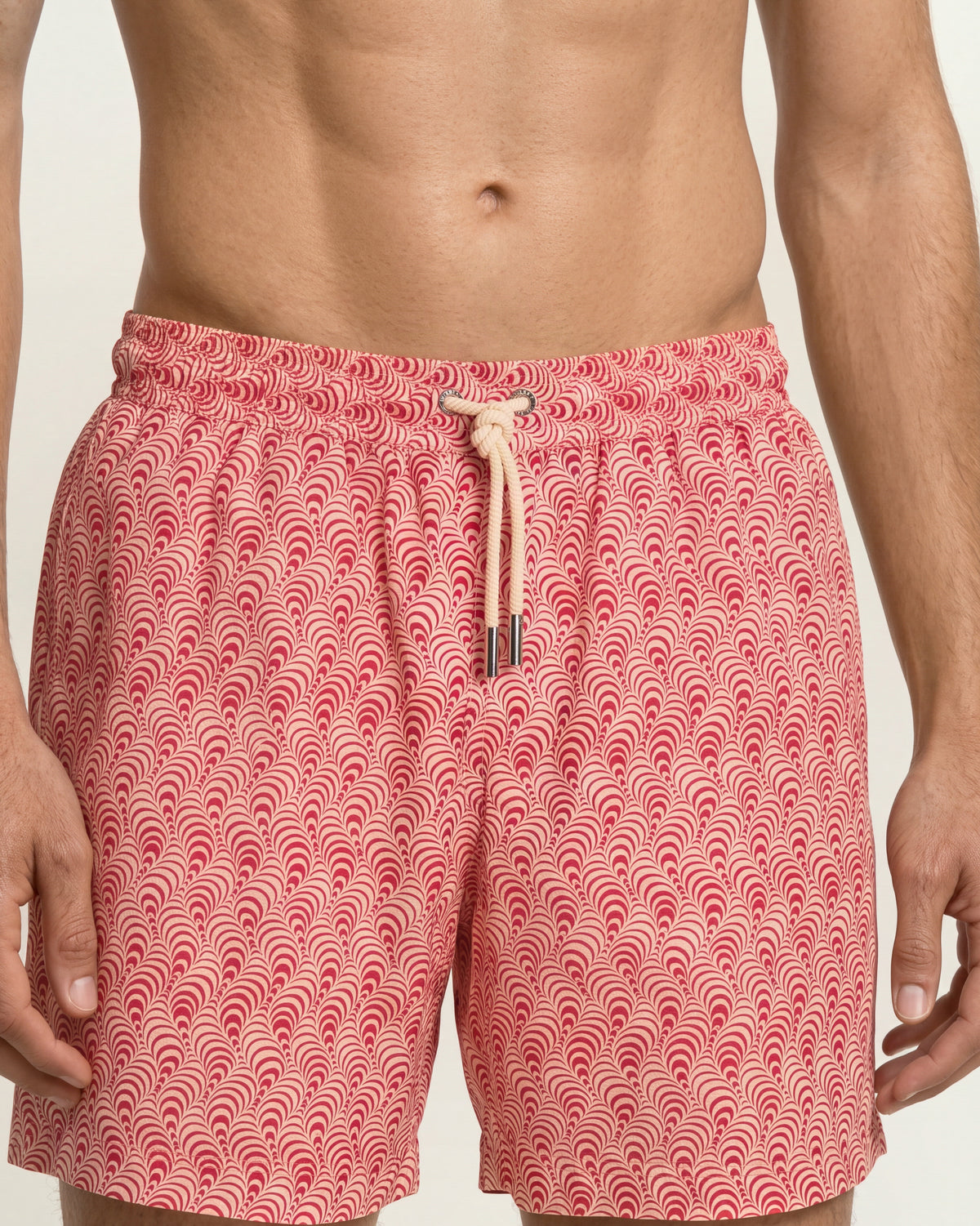 Man wearing red patterned with drawcord waist swim shorts on a white background 