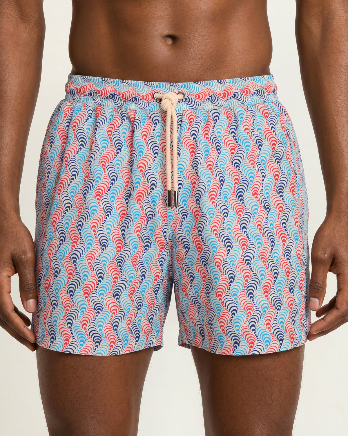 Man wearing multicolored patterned drawcord waist swim shorts on a white background.