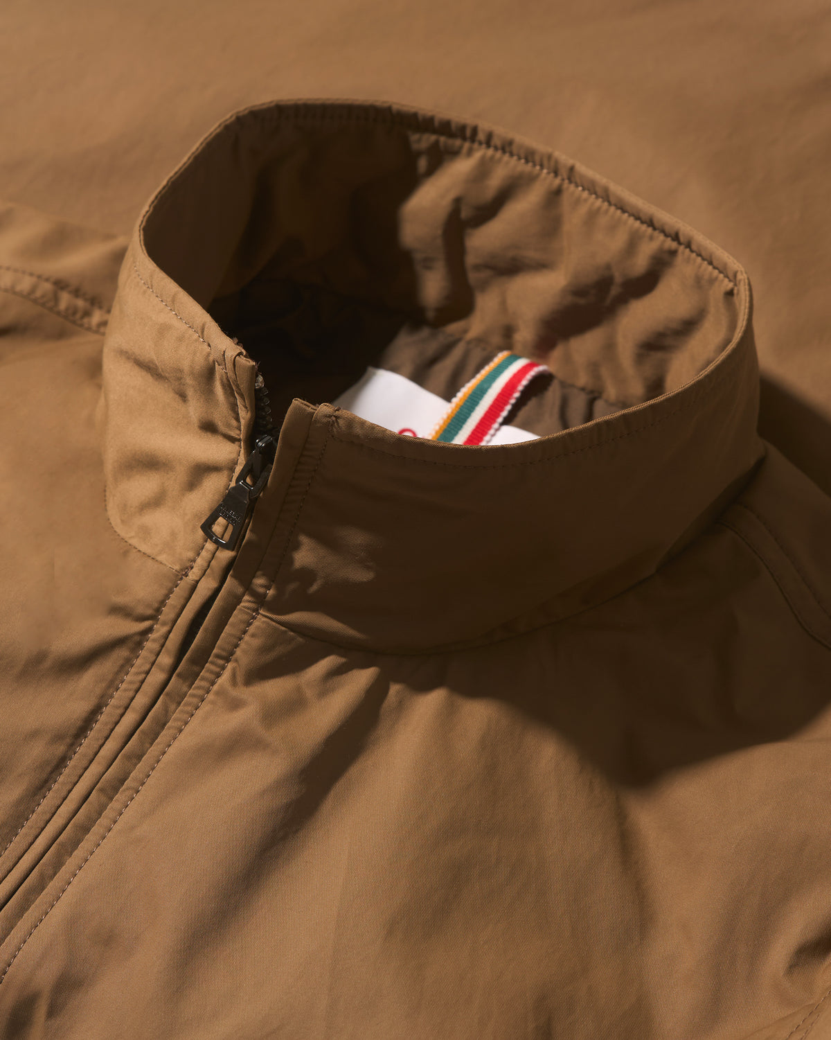 Closeup of bronze coloured padded jacket, showing zip up and collar detail