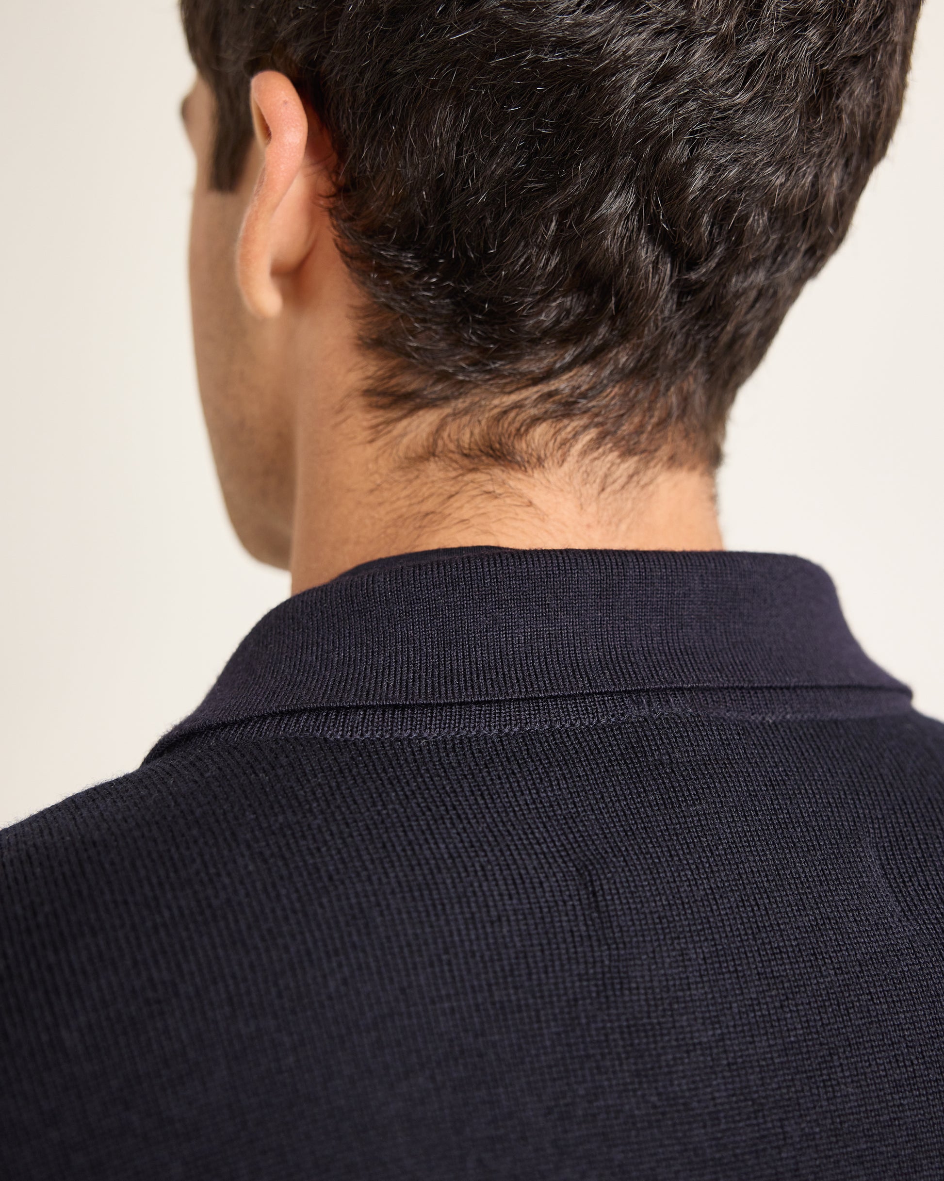 Closeup detail of navy knitted jacket on a plain background