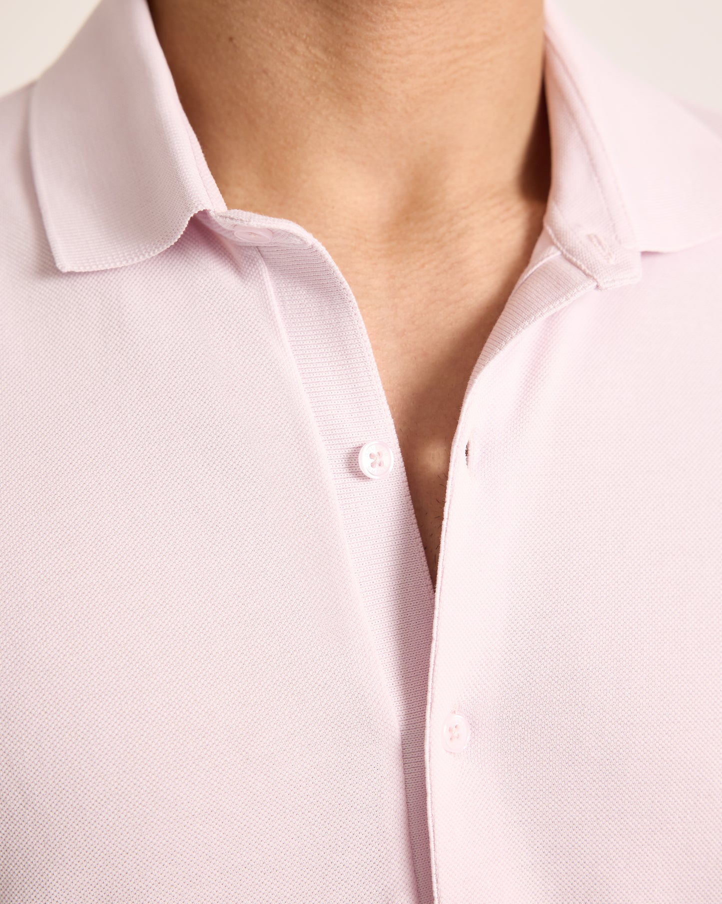 Close-up of a light pink shirt with a collar and button detail.