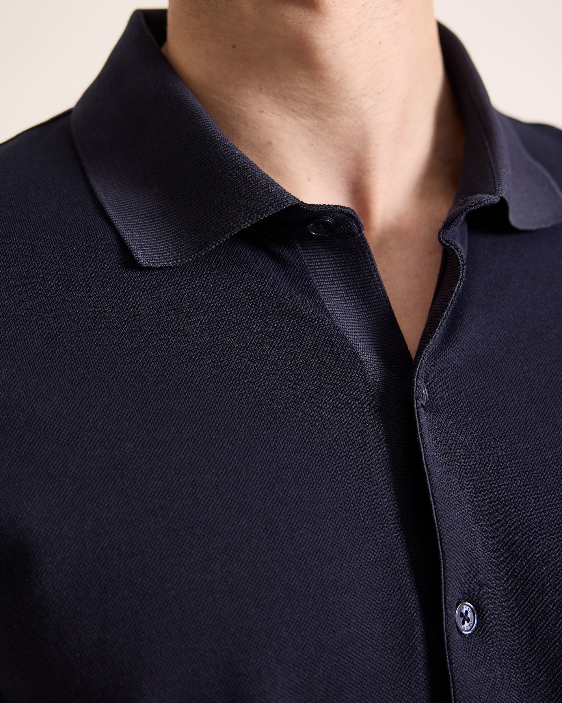 Person wearing navy polo shirt with closeup of collar detail