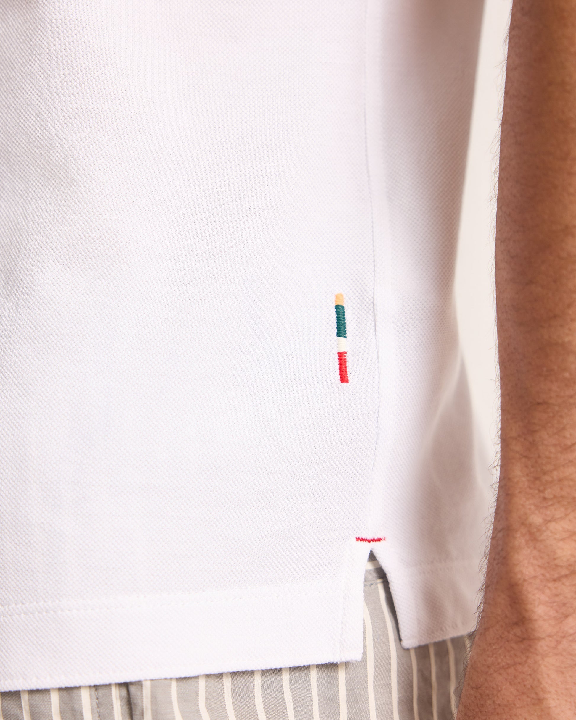 Close-up of a white shirt with colorful embroidery on a person wearing it.