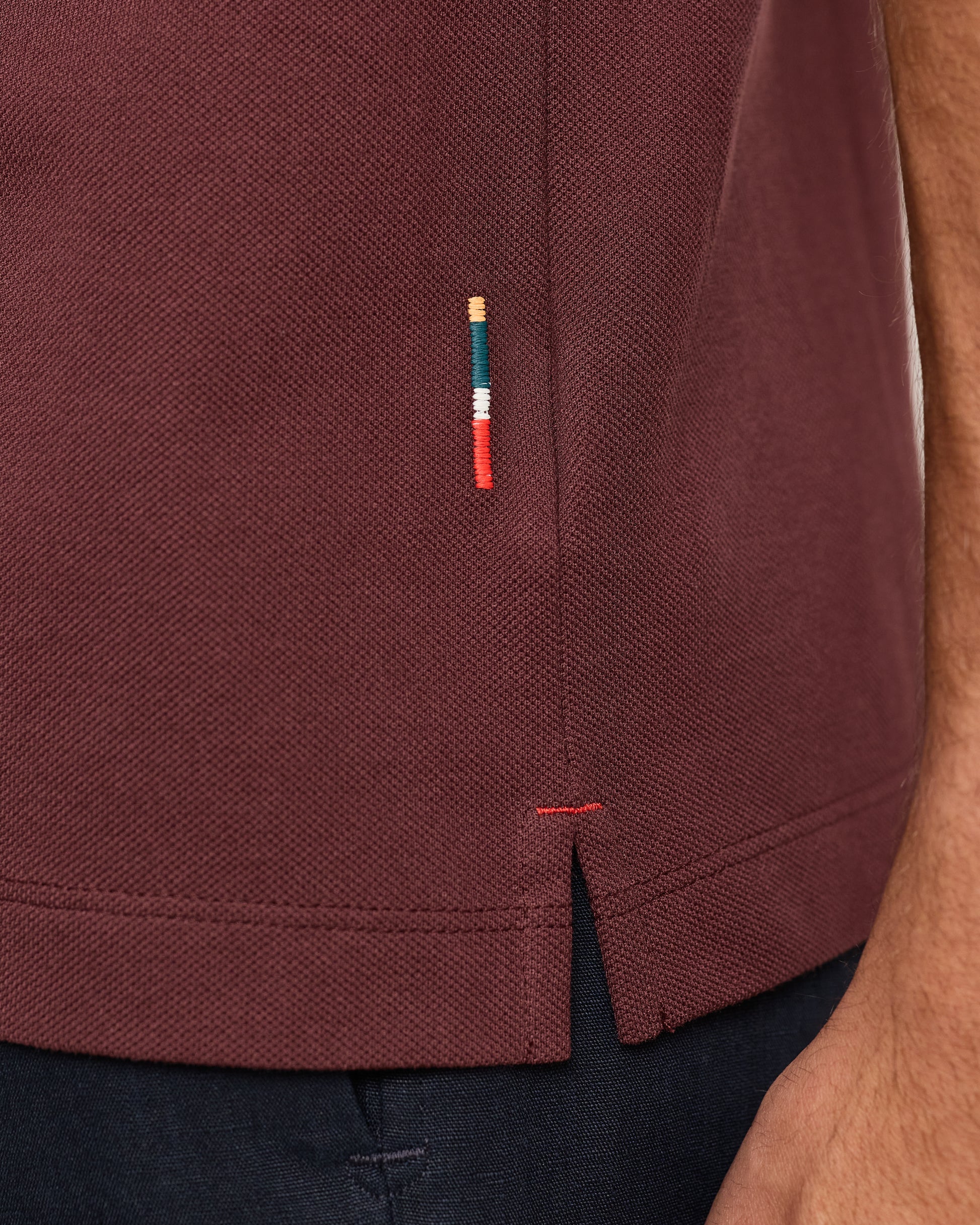 Close-up of a maroon polo shirt with a small embroidered logo on the side.