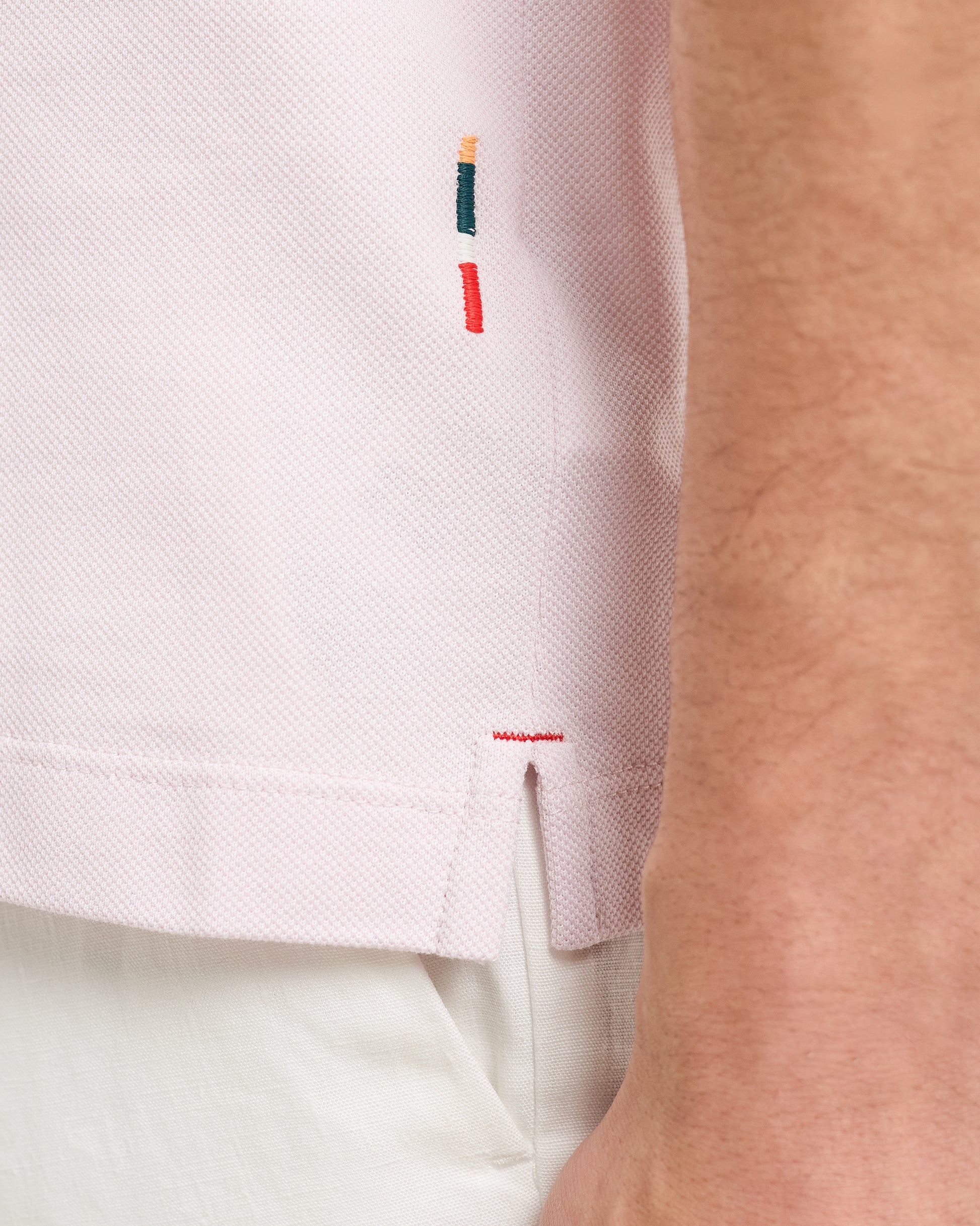 Close-up of a light pink shirt with embroidered details on a person wearing it.