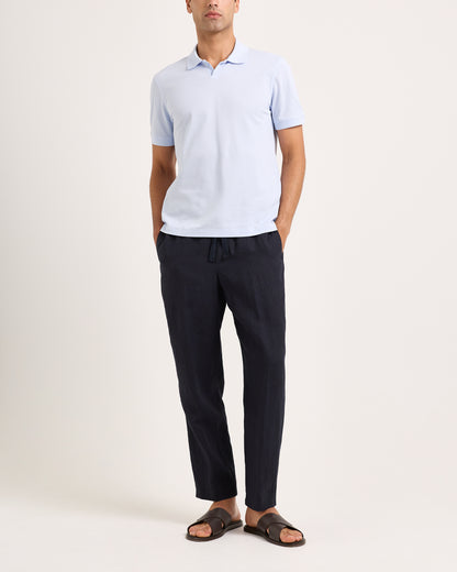 Man wearing a light blue polo shirt and dark pants on a white background