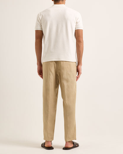 Model wearing light cream polo with beige trousers on a white background