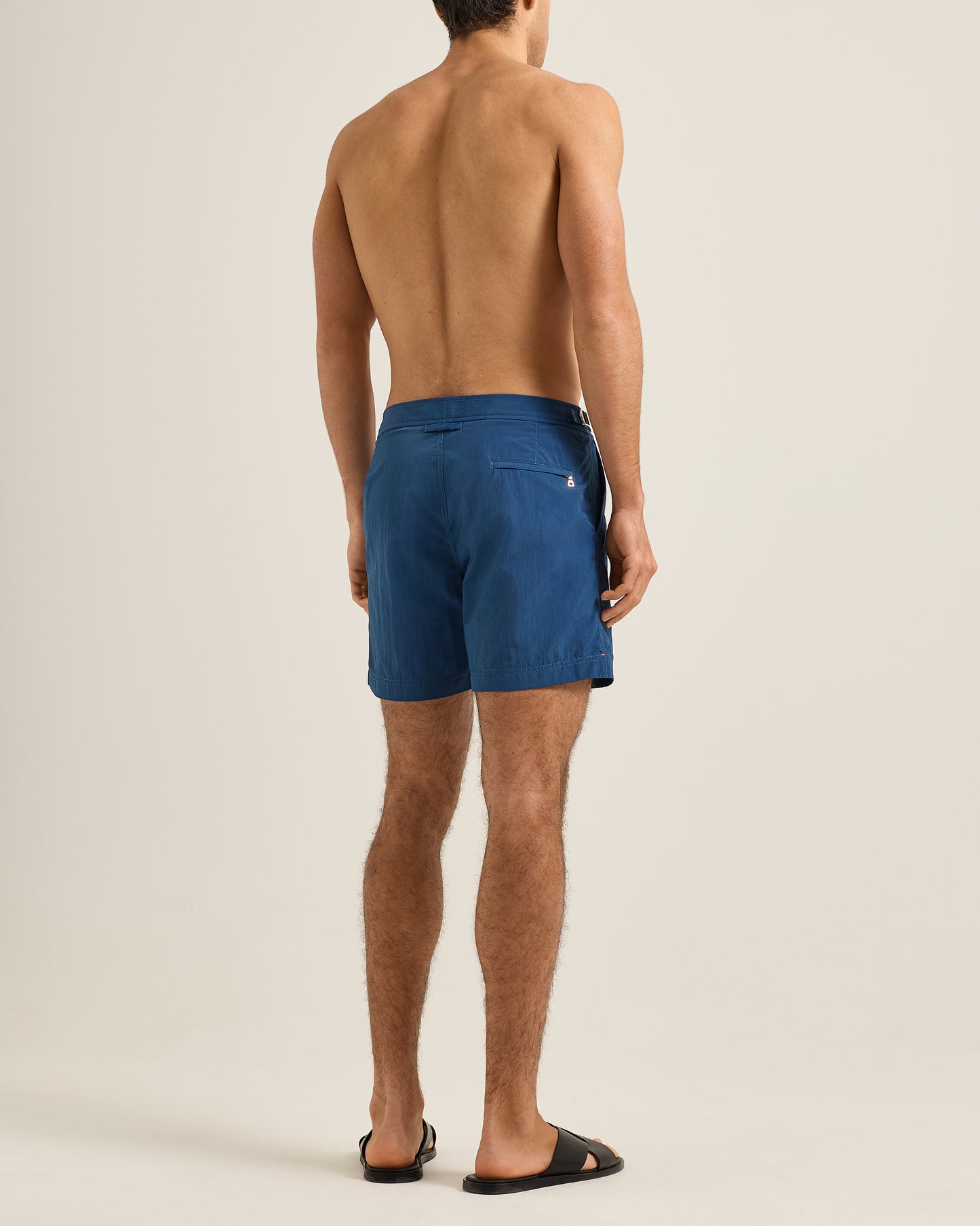Man wearing blue swim shorts on a beige background