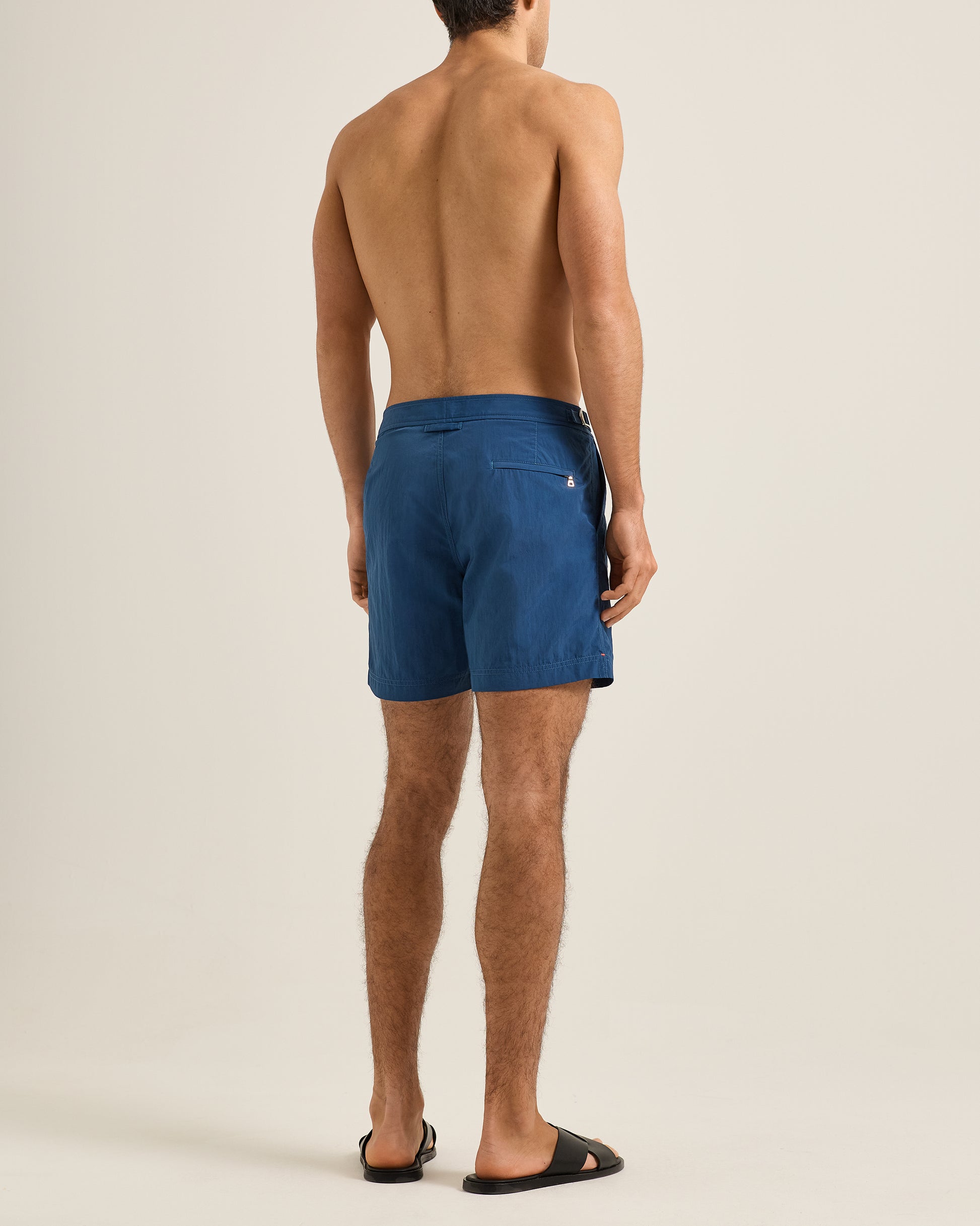 Man wearing blue swim shorts on a beige background