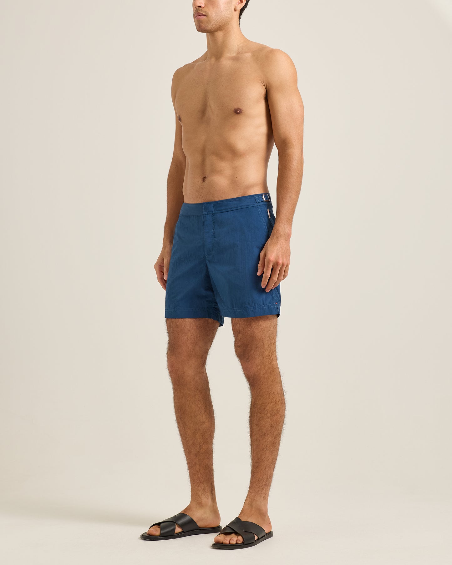 Man wearing blue swim shorts on a beige background