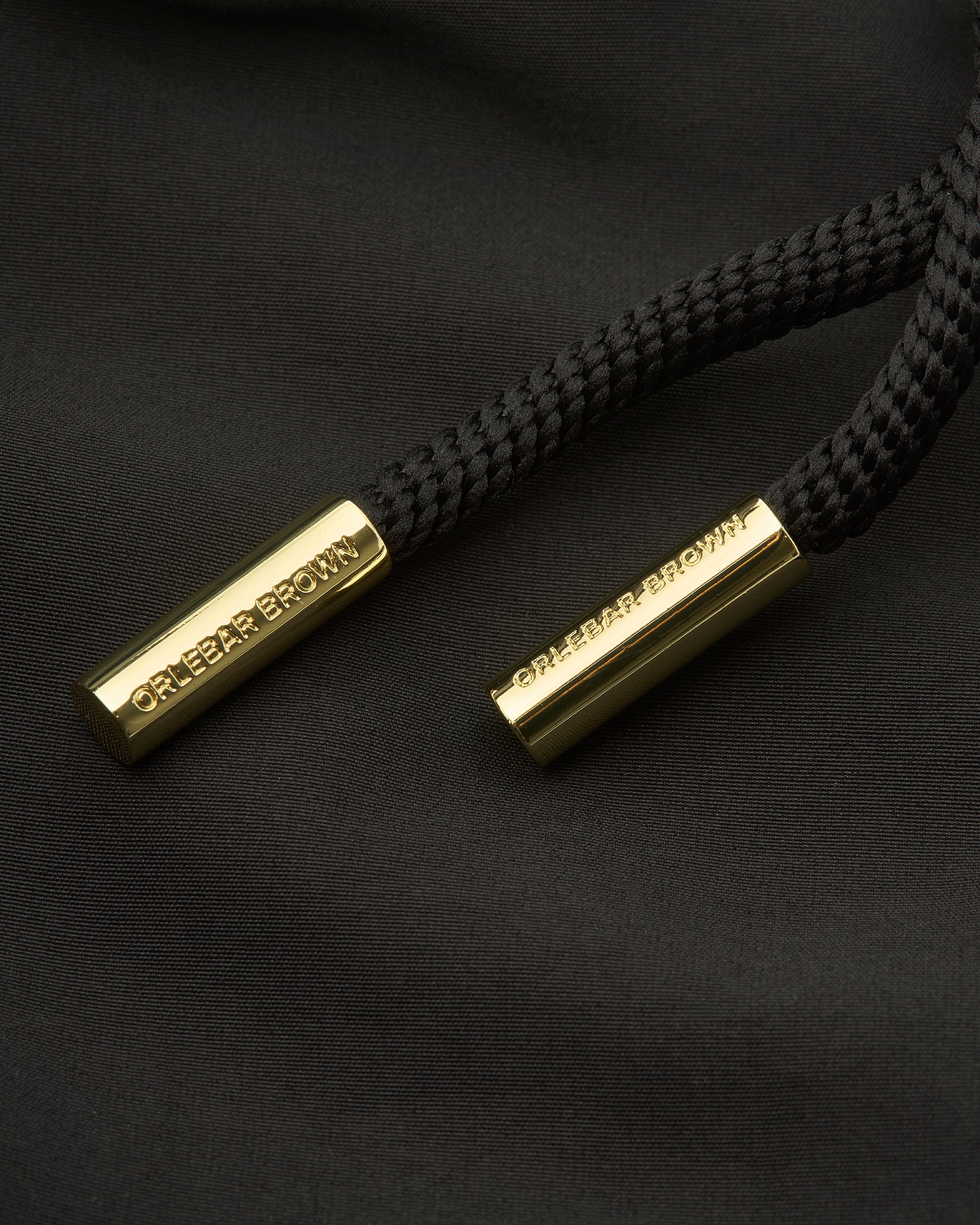 Black braided shoelaces with gold metal tips on a black background