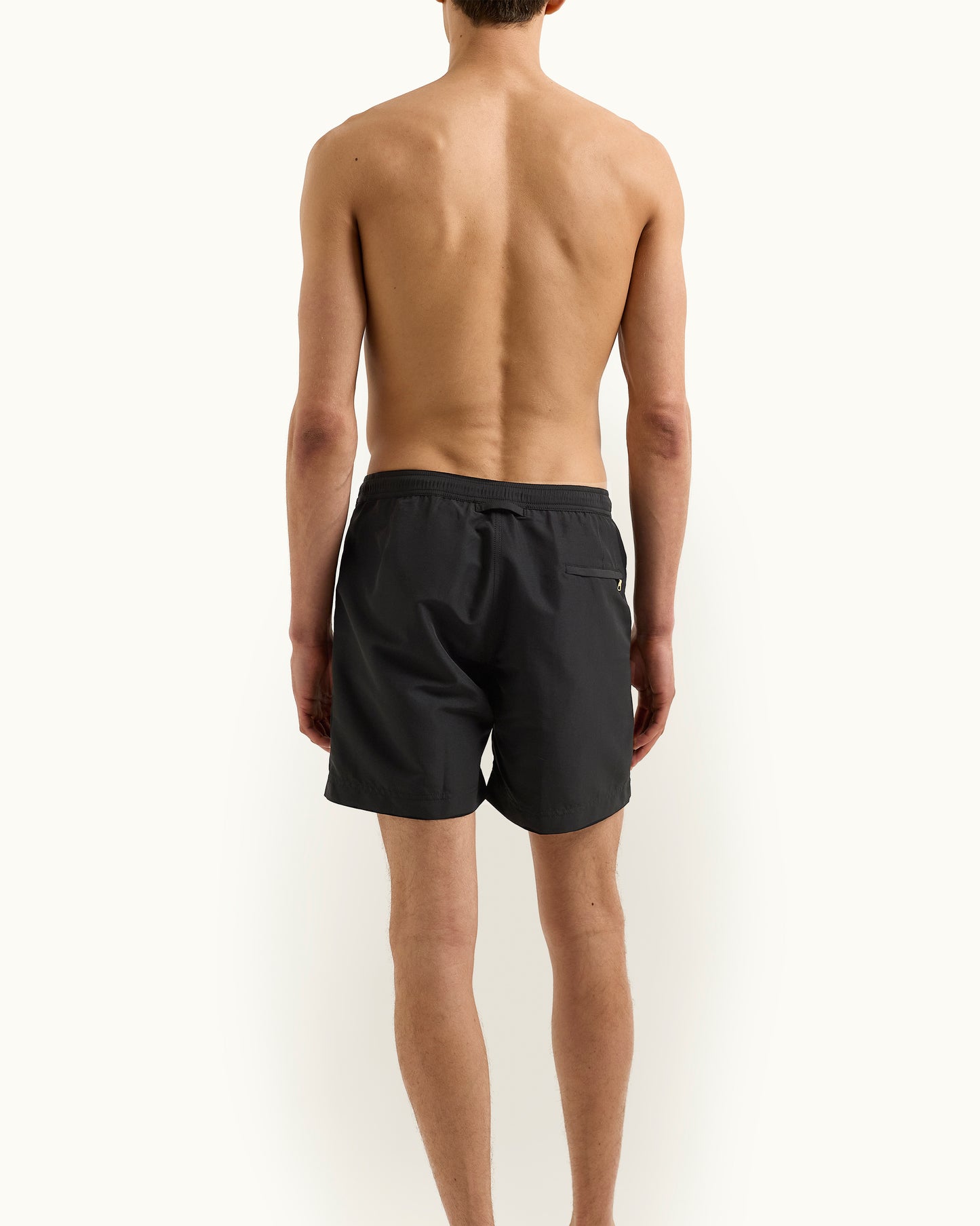 Person wearing black swim shorts on a white background