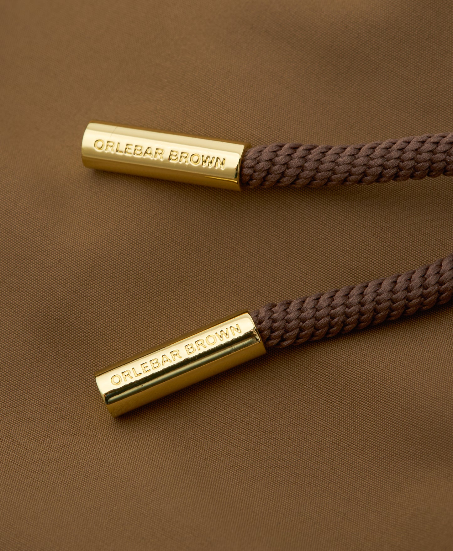 Two brown braided cords with gold ends featuring 'OLEBAR BROWN' branding on a brown background.