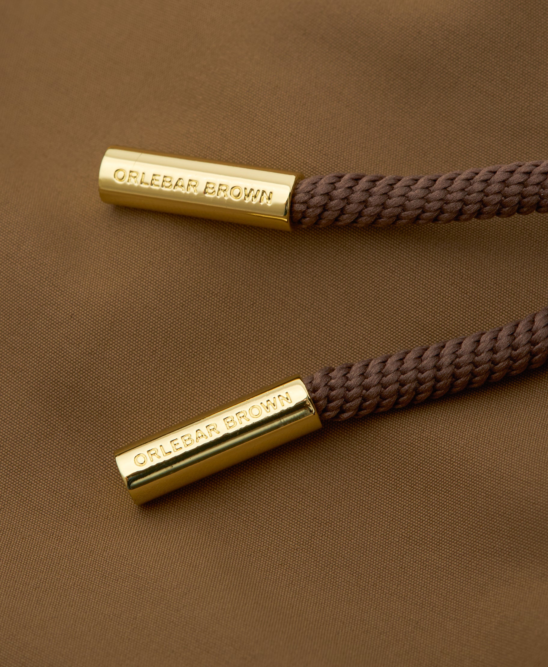 Two brown braided cords with gold ends featuring 'OLEBAR BROWN' branding on a brown background.