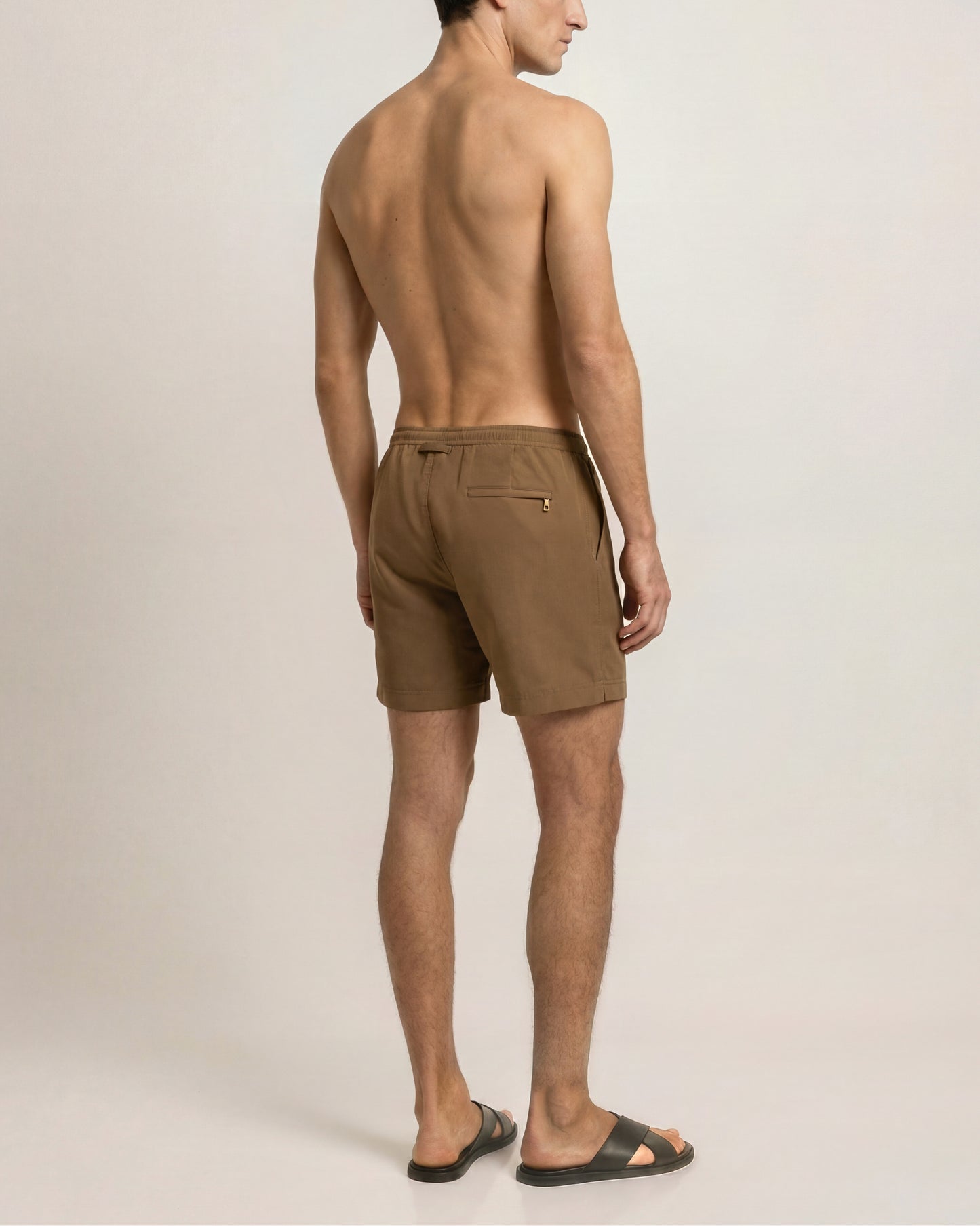 Man wearing brown shorts on a plain background