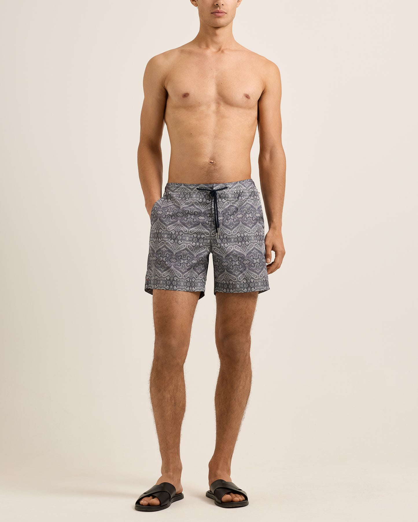 Man wearing patterned swim shorts on a beige background