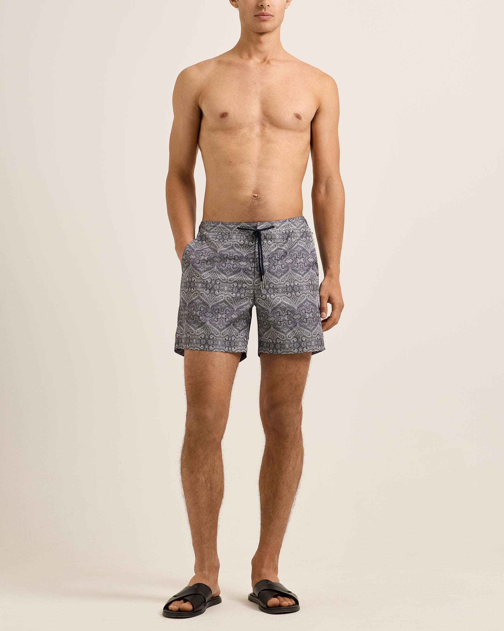 Man wearing patterned swim shorts on a beige background