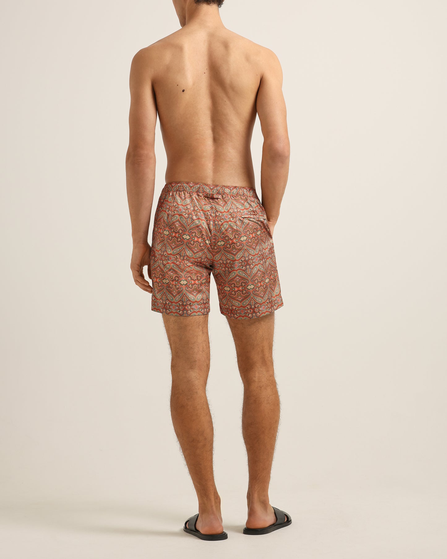 Man wearing patterned swim shorts on a plain background