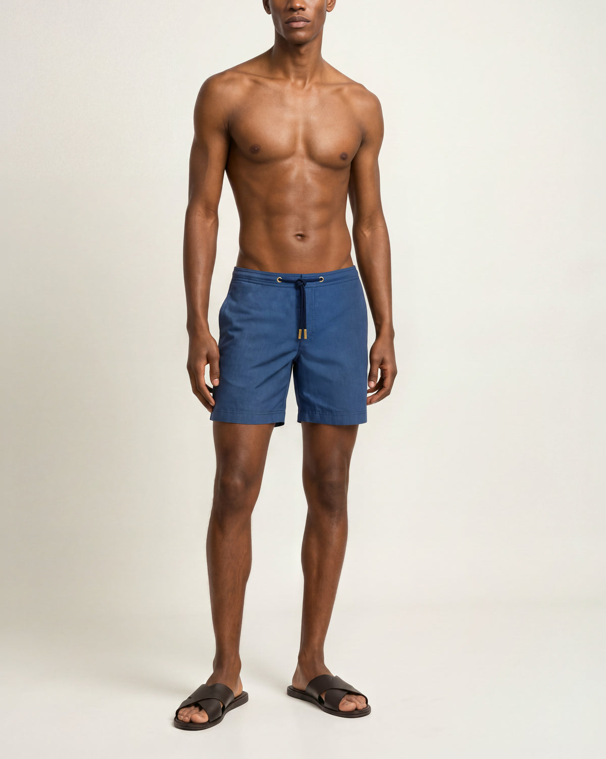 Man wearing aquamarine drawcord swim shorts with a navy robe on a plain background