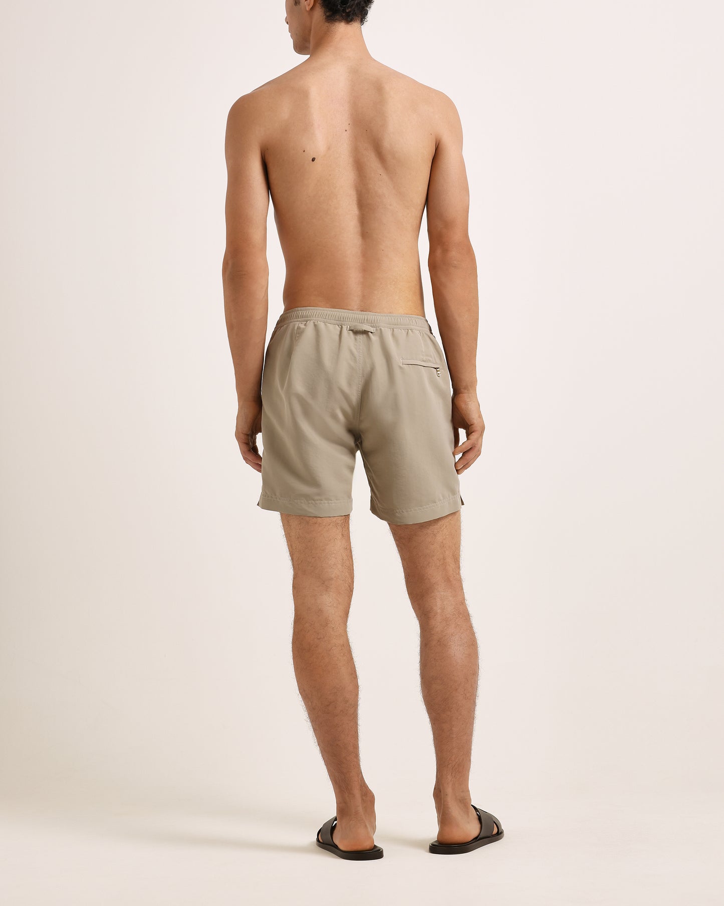 Man wearing beige shorts on a plain background
