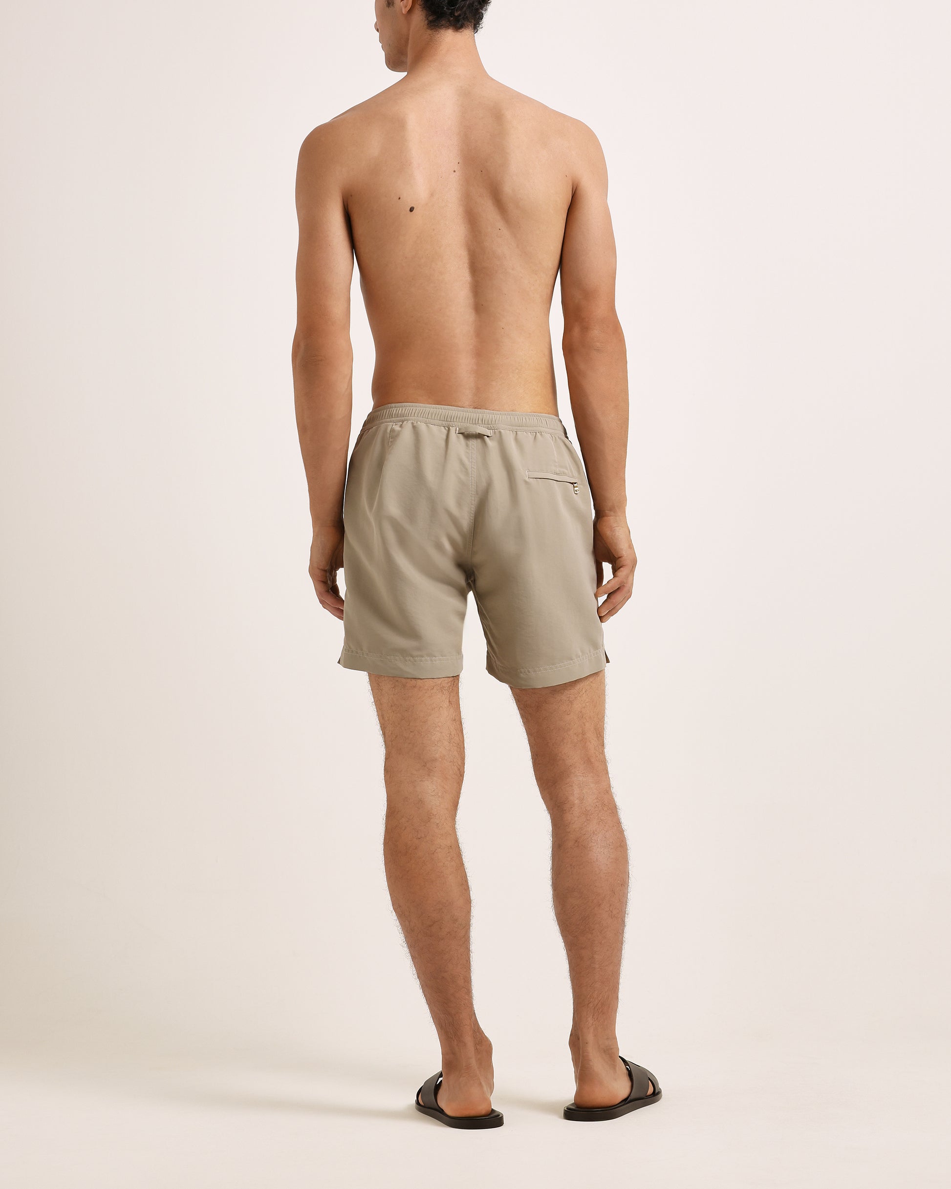 Man wearing beige shorts on a plain background