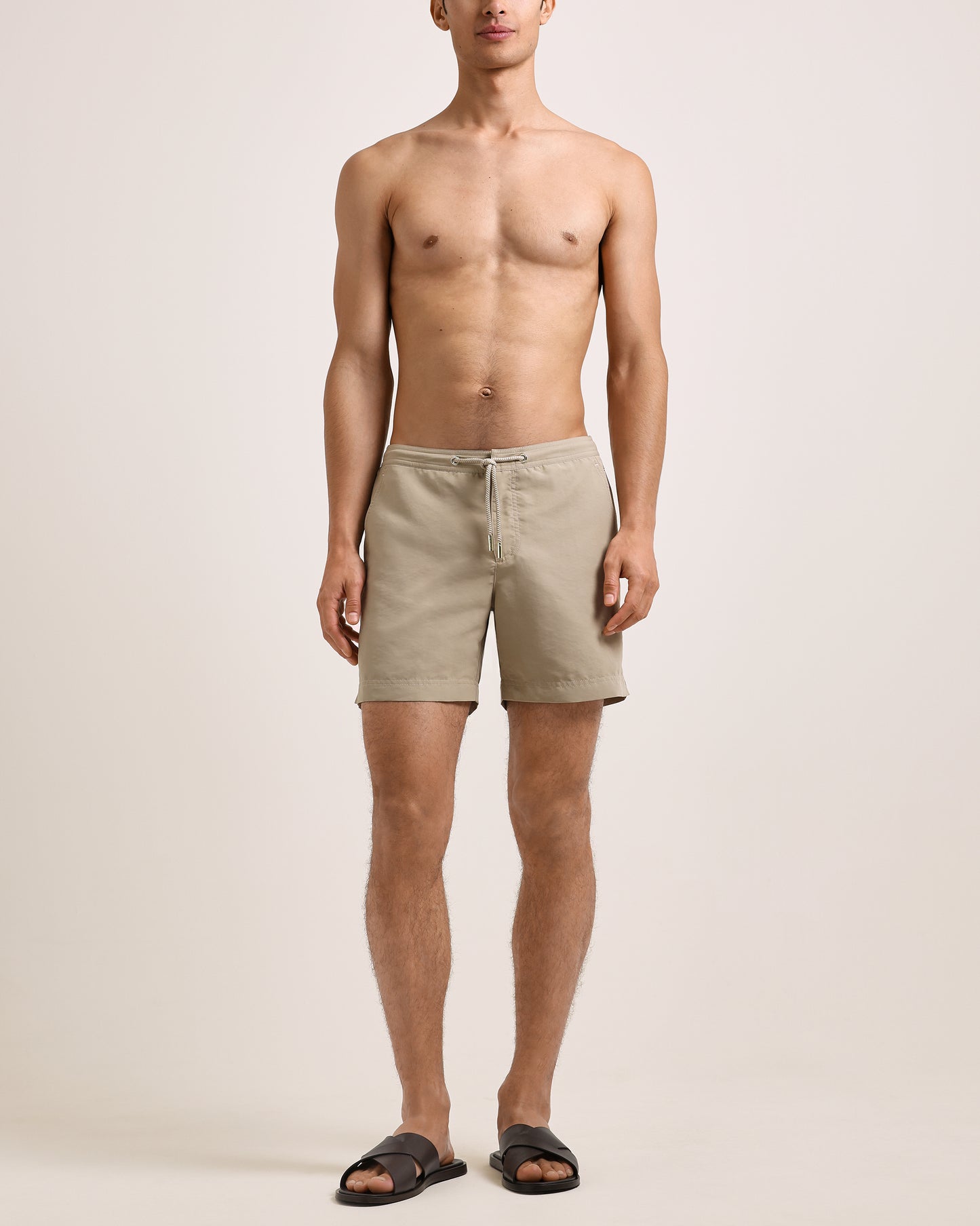 Man wearing beige shorts on a plain background