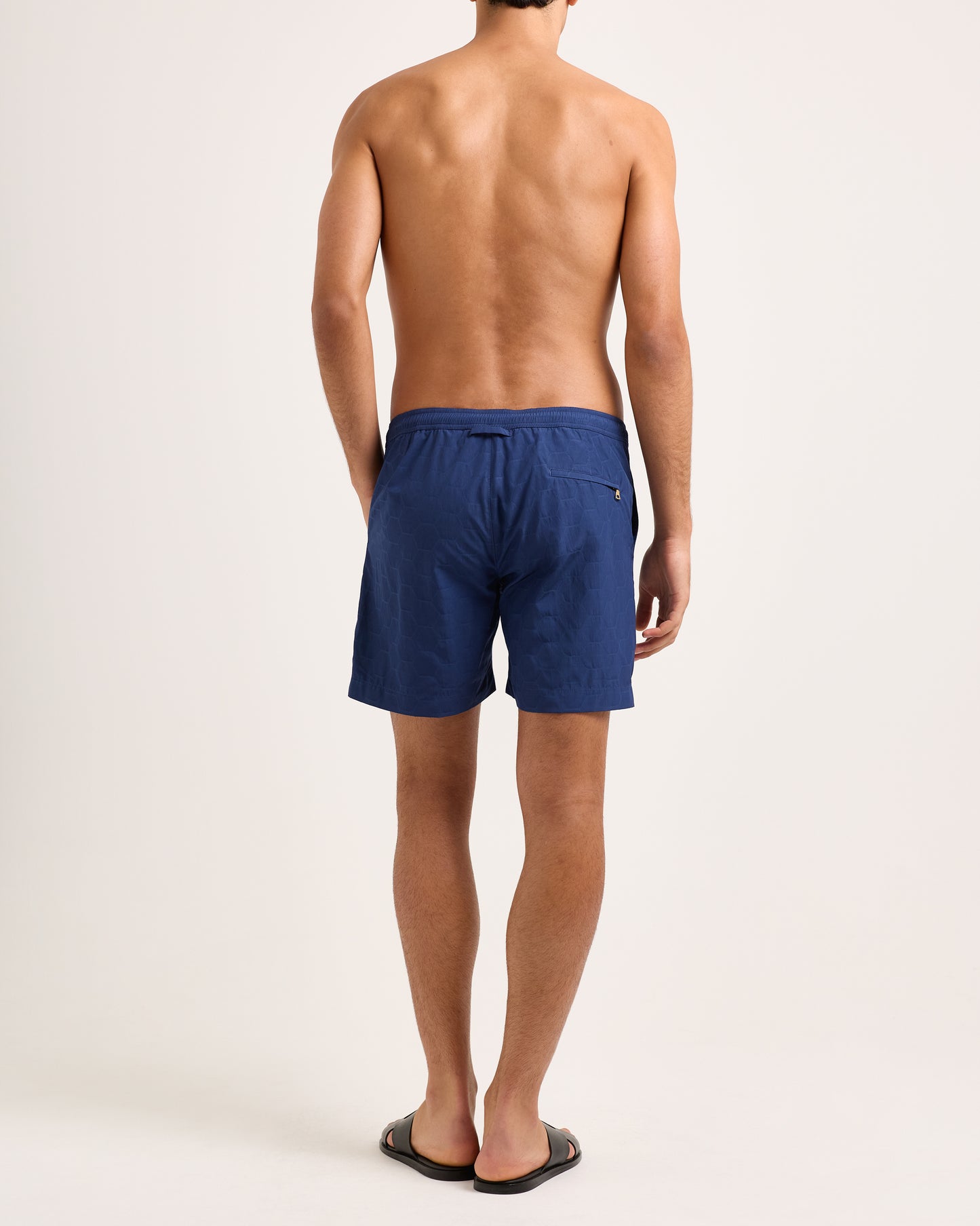 Person wearing blue swim shorts on a plain background