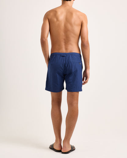 Person wearing blue swim shorts on a plain background