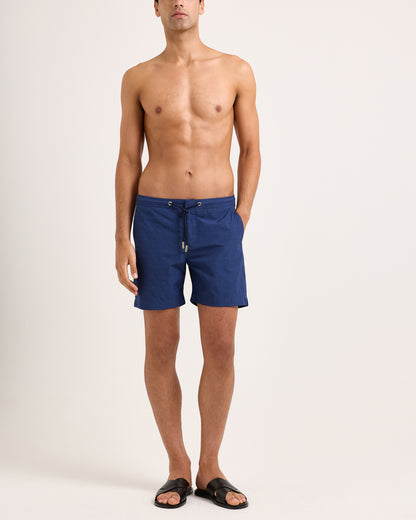 Man wearing blue swim shorts on a white background