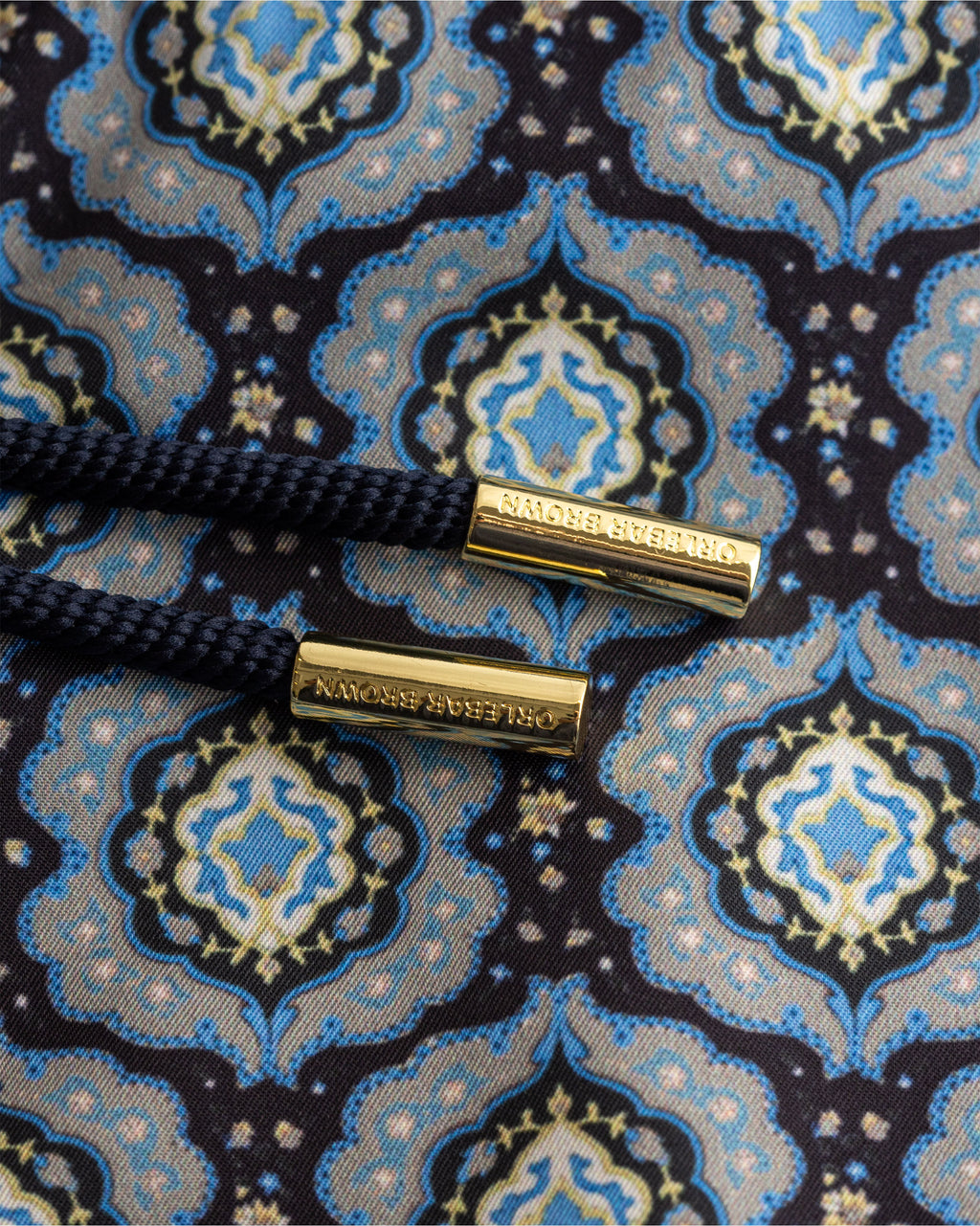 Close-up of a patterned fabric with gold buttons on a blue and black background