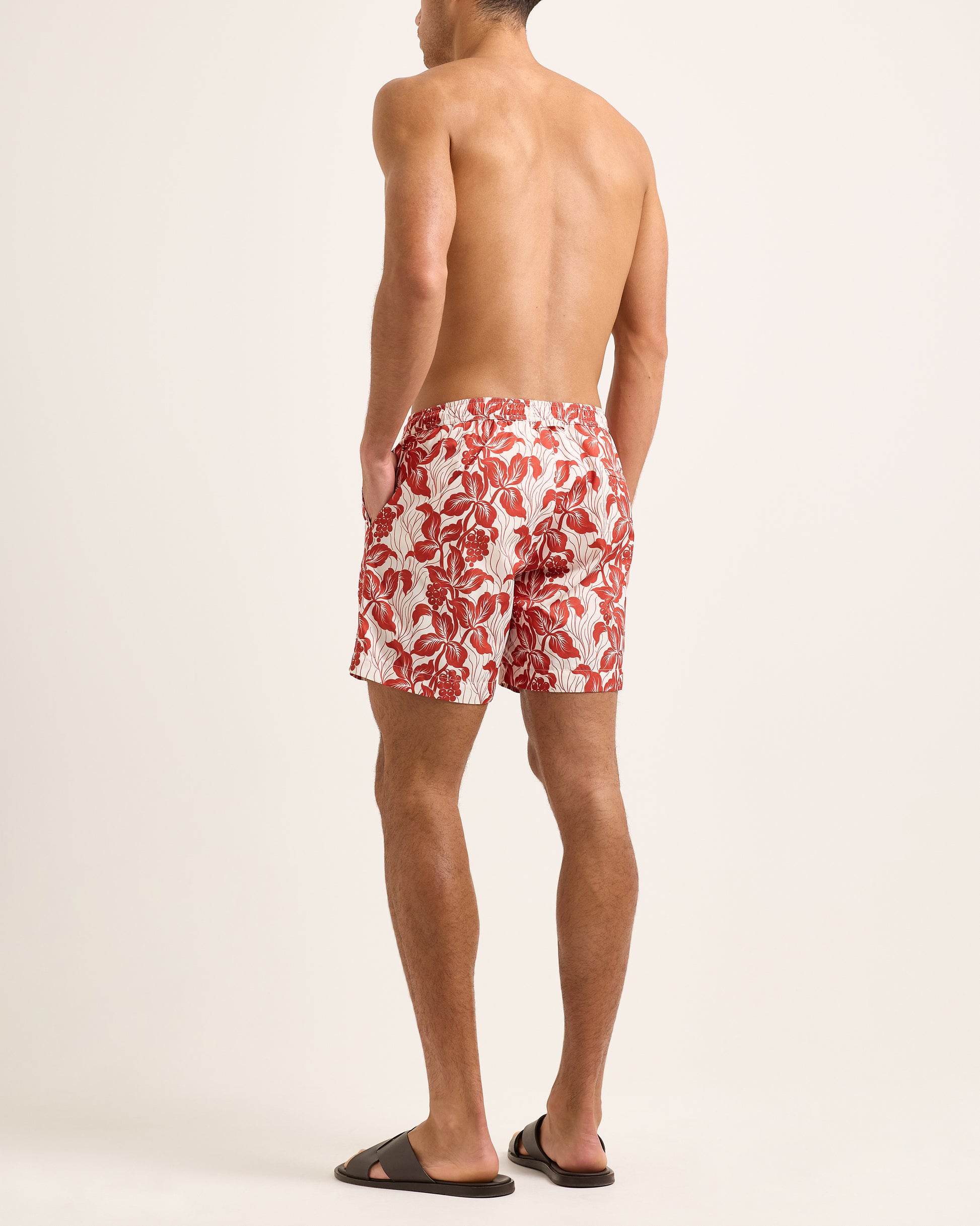 Man wearing red floral swim shorts on a white background
