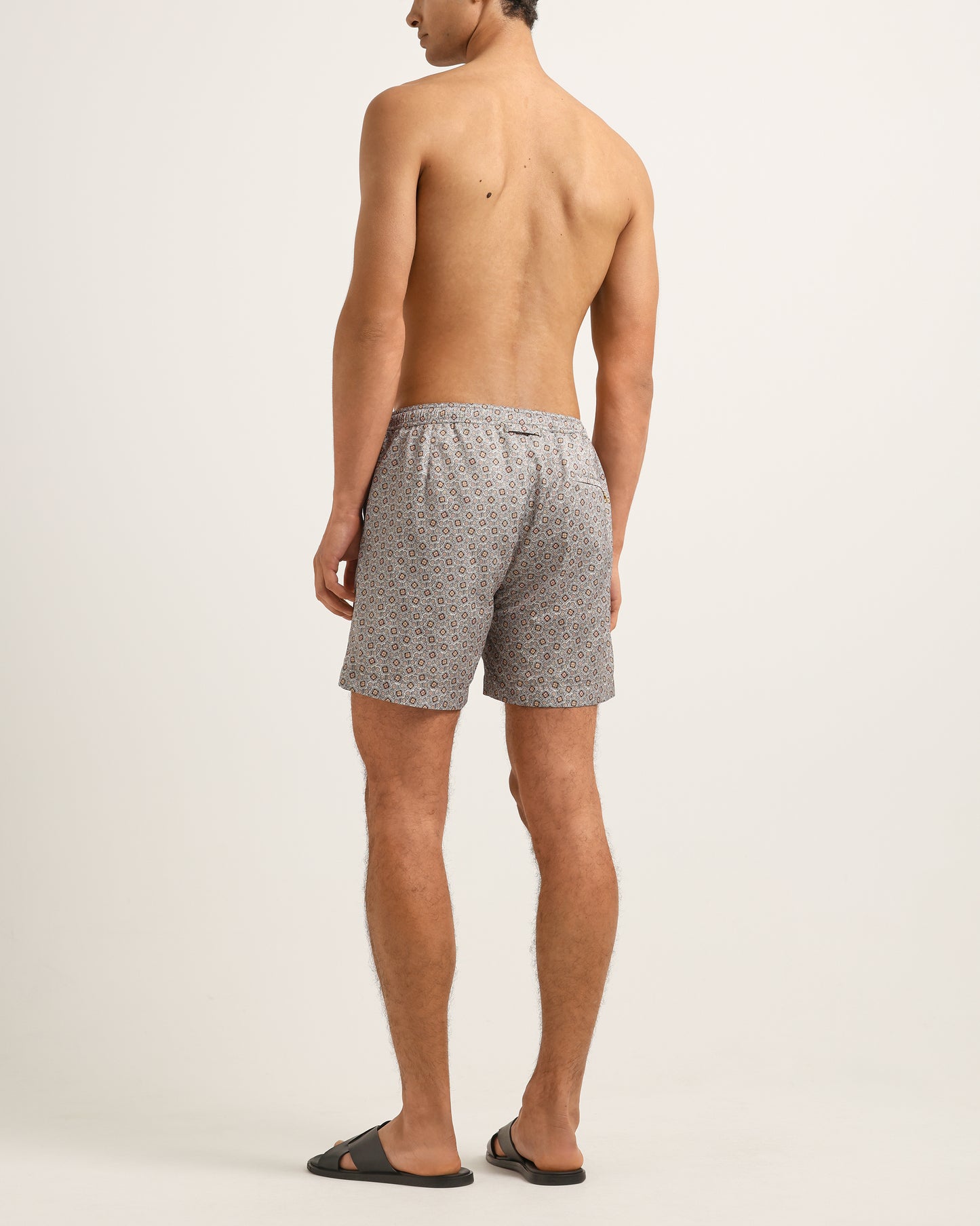 Man wearing gray patterned shorts on a plain background