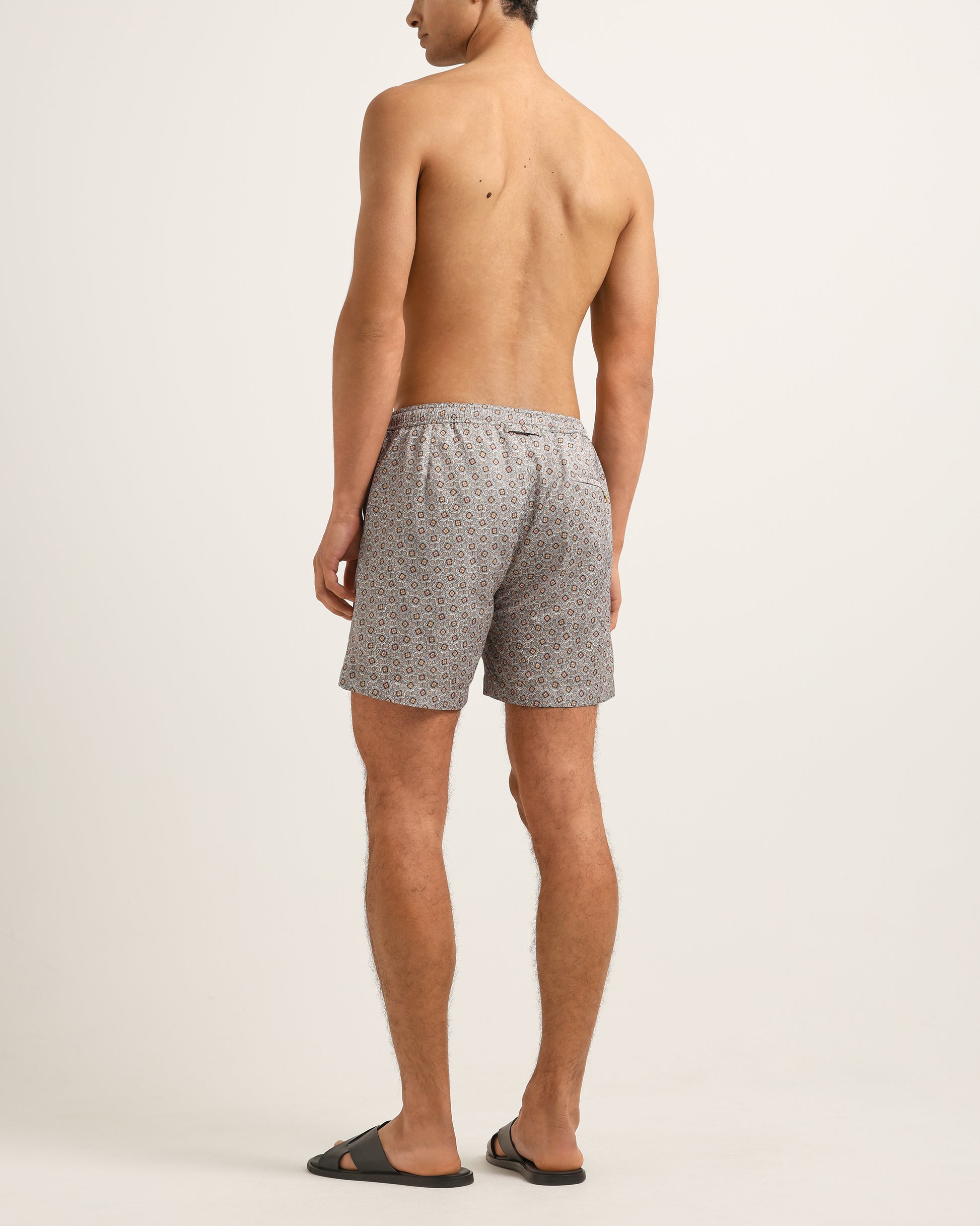 Man wearing gray patterned shorts on a plain background