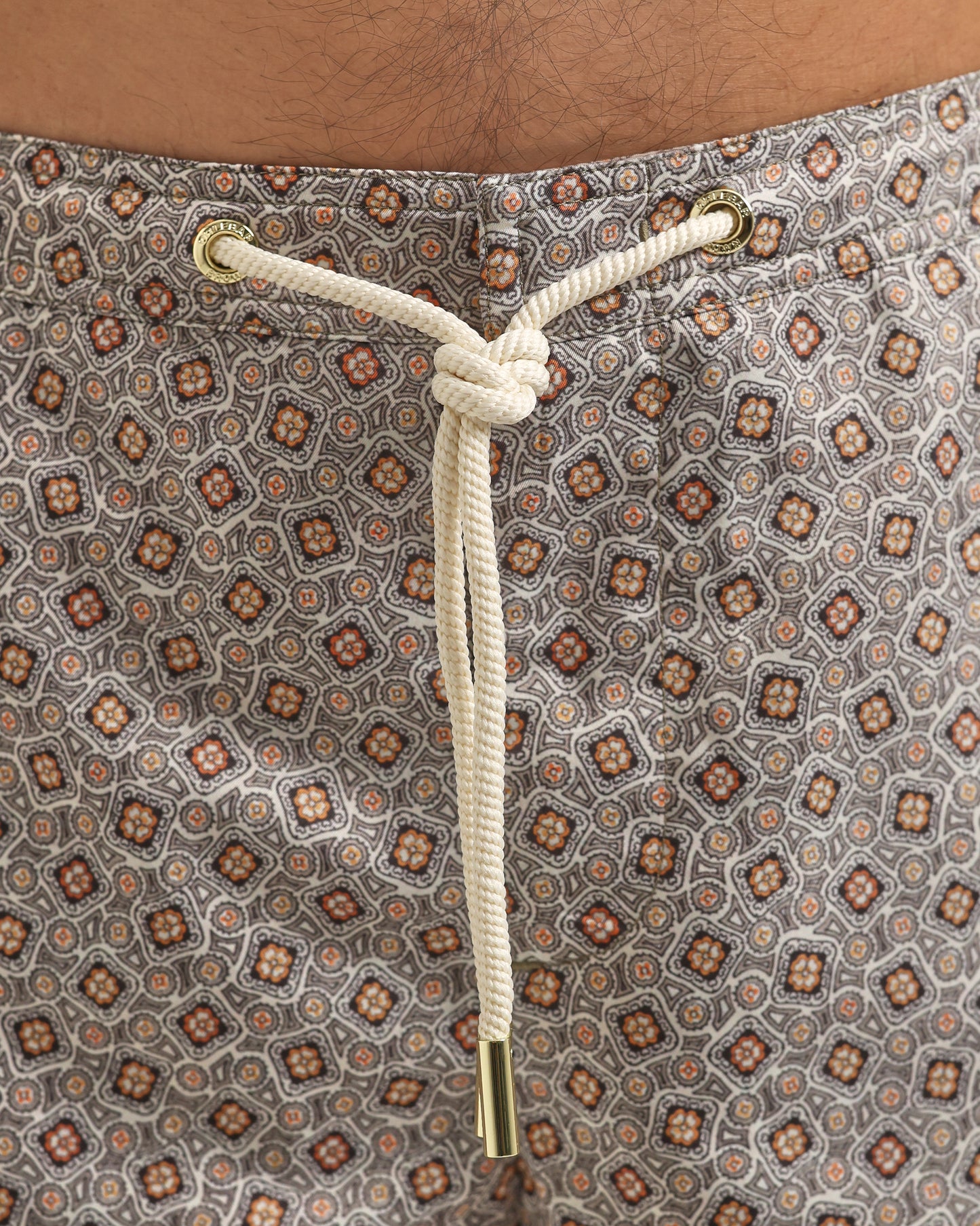 Close-up of a patterned fabric with a drawstring and gold knot.