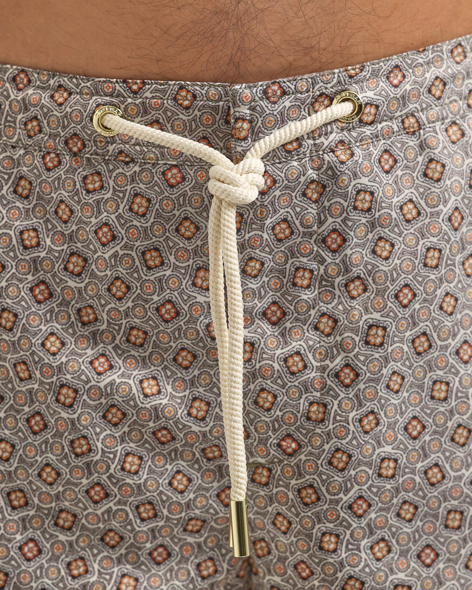 Close-up of a patterned fabric with a drawstring and gold knot.