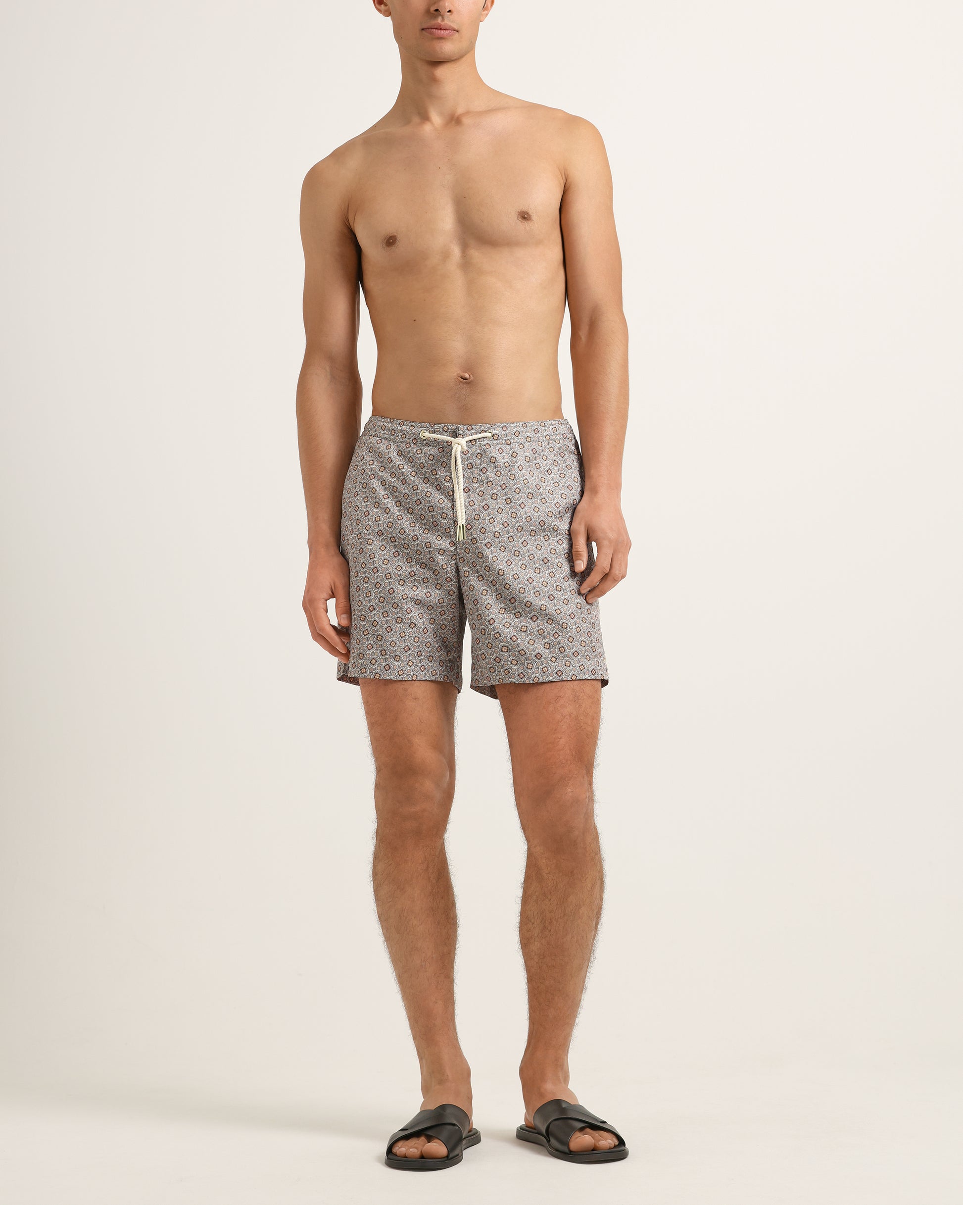 Man wearing patterned shorts on a plain background