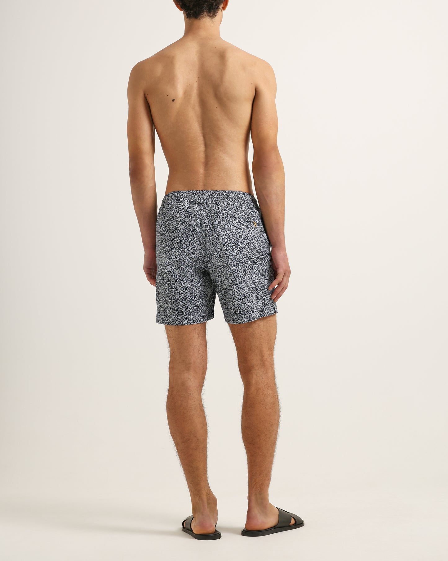 Man wearing patterned swim shorts on a plain background