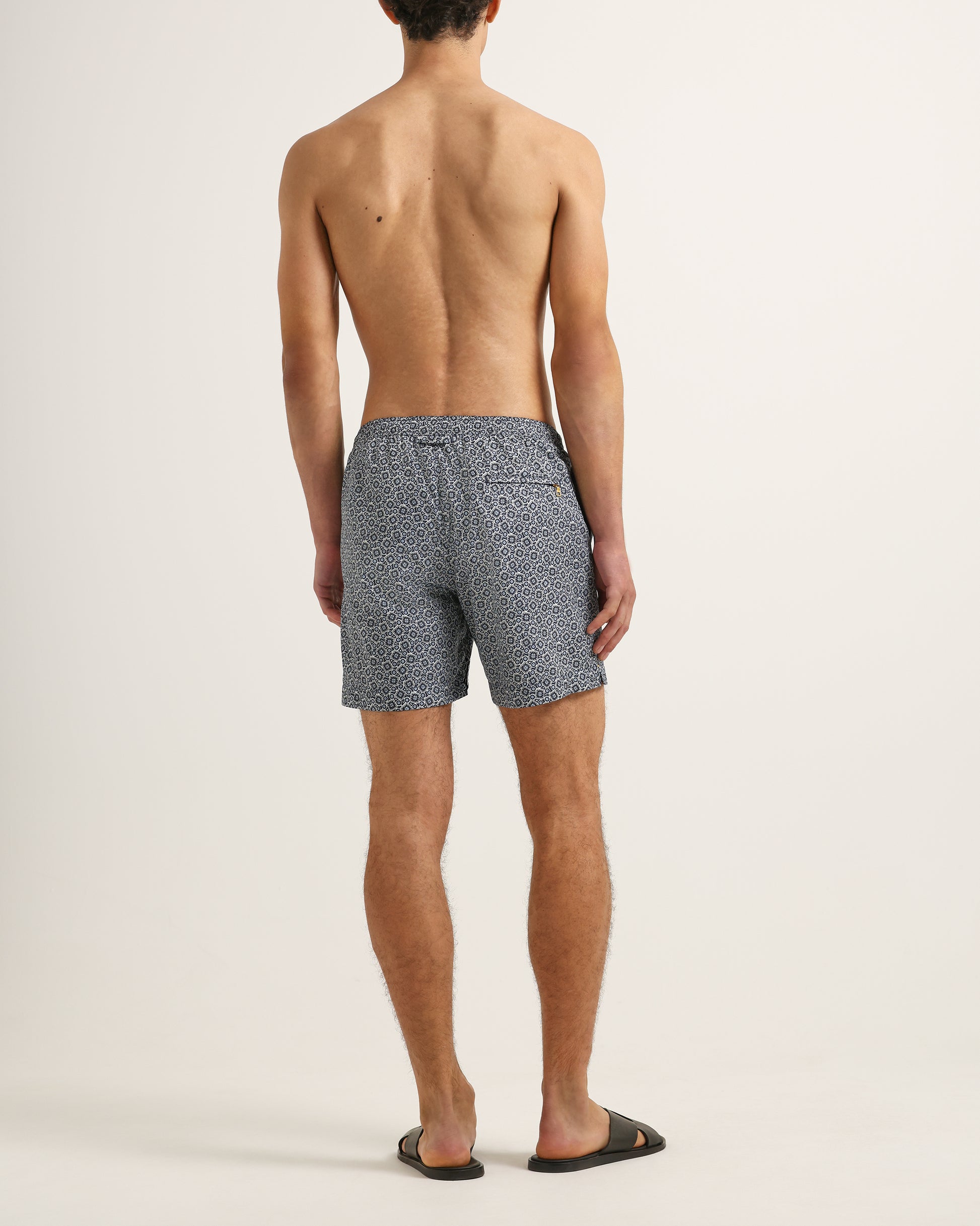 Man wearing patterned swim shorts on a plain background