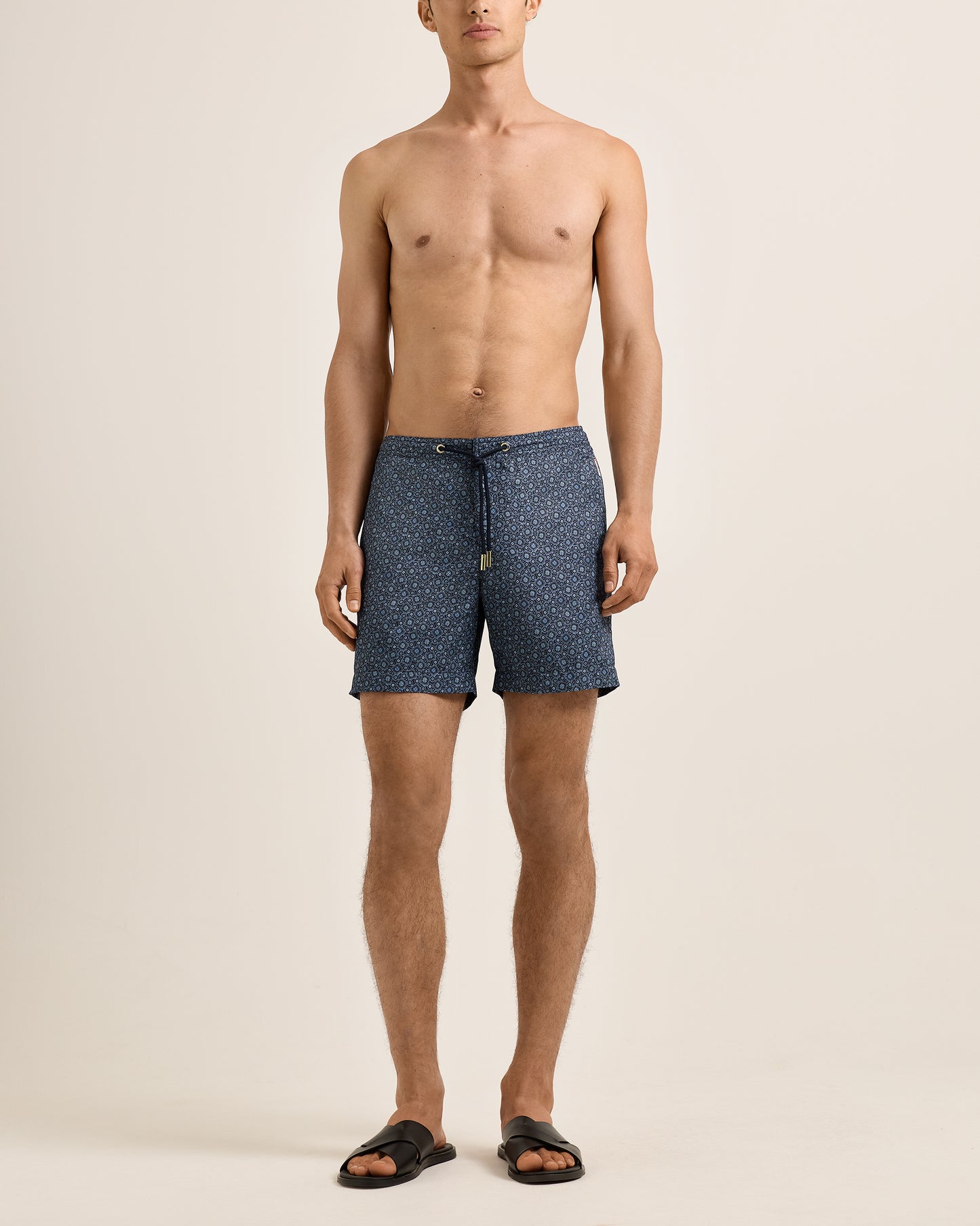 Man wearing blue patterned shorts on a beige background