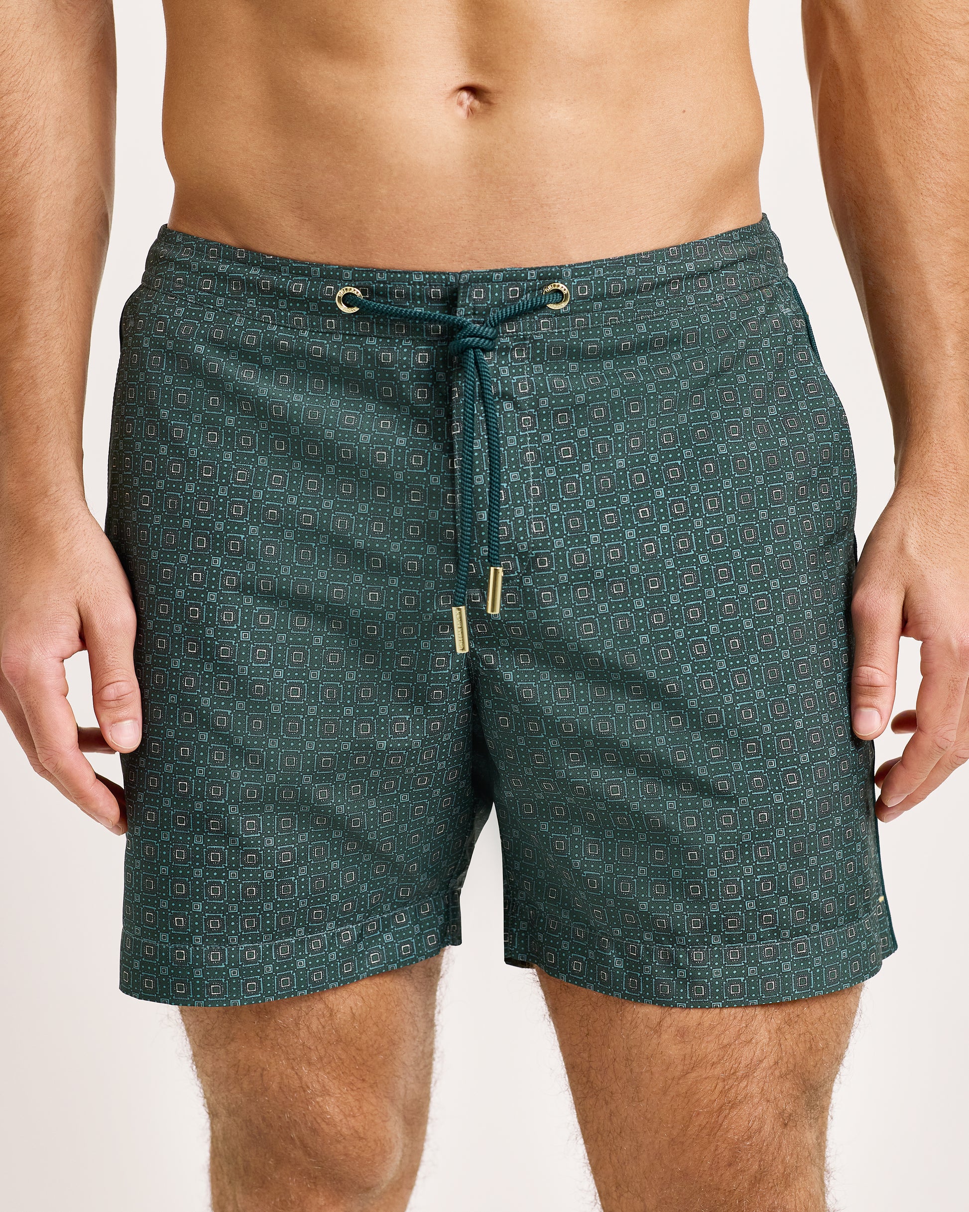 Green patterned swim shorts worn by a person on a plain background
