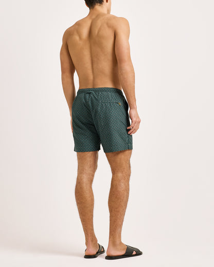 Man wearing green patterned swim shorts on a white background