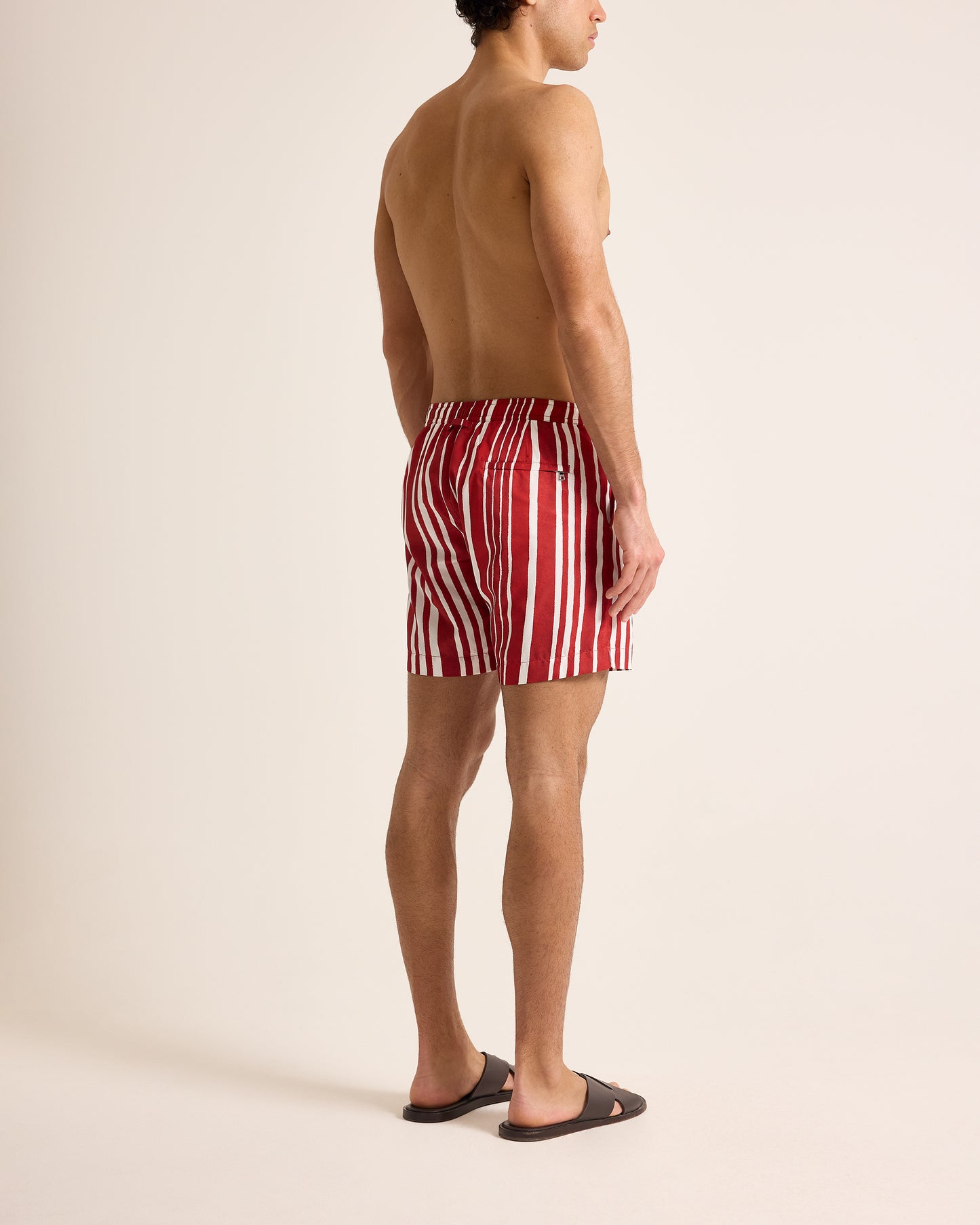 Person wearing red and white striped swim shorts on a plain background