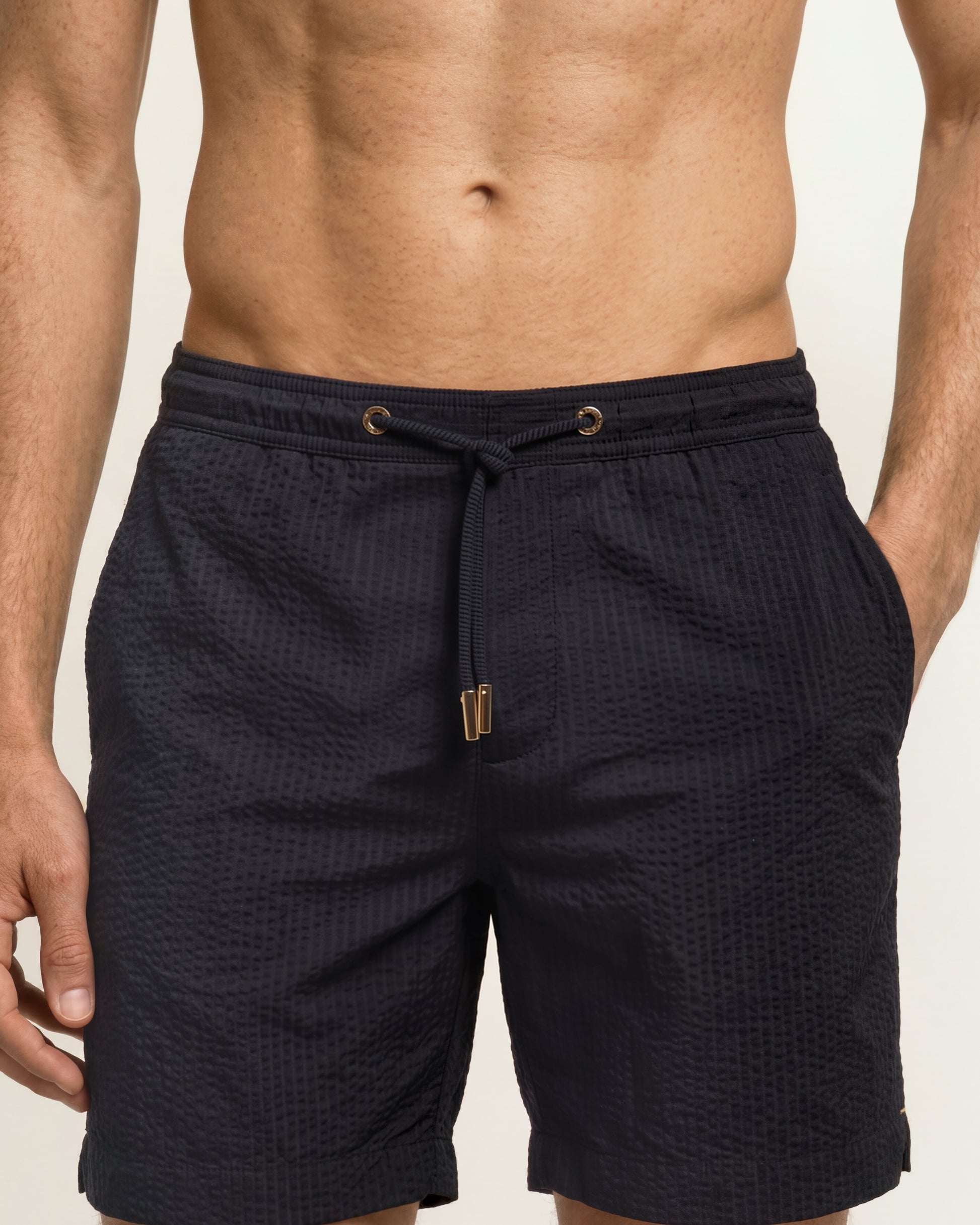 Close up of Navy seersucker drawcord swimshorts on a model on a white background