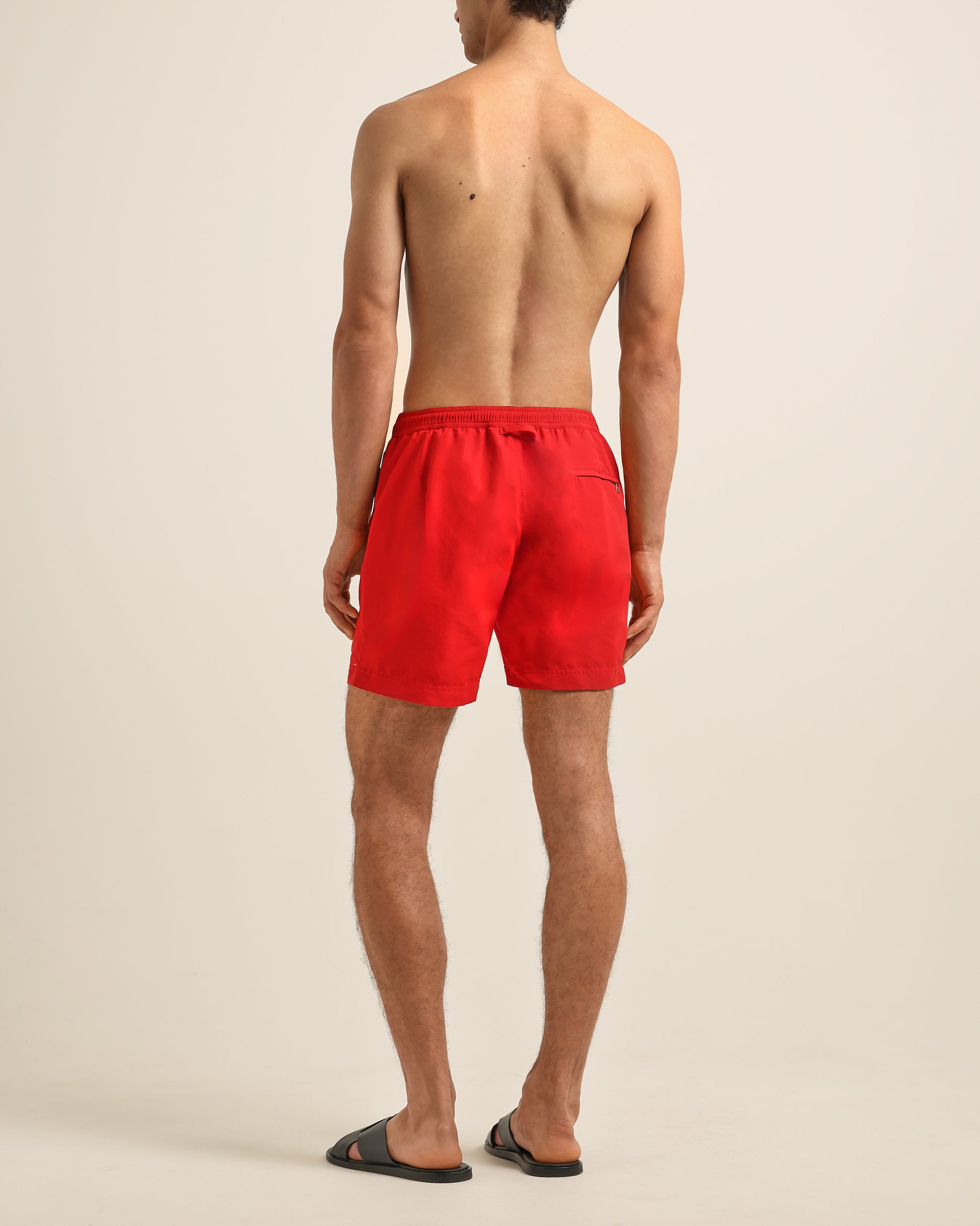 Person wearing red swim shorts on a plain background