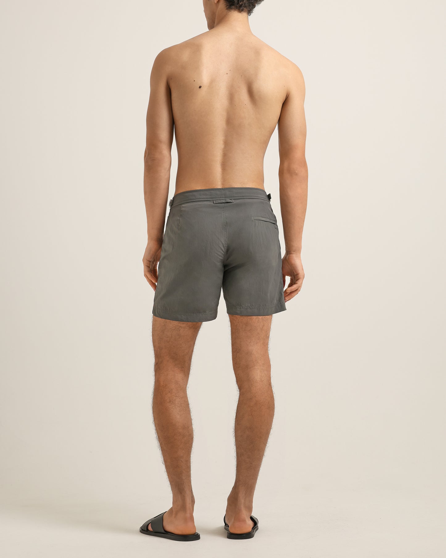 Man wearing gray swim shorts on a beige background